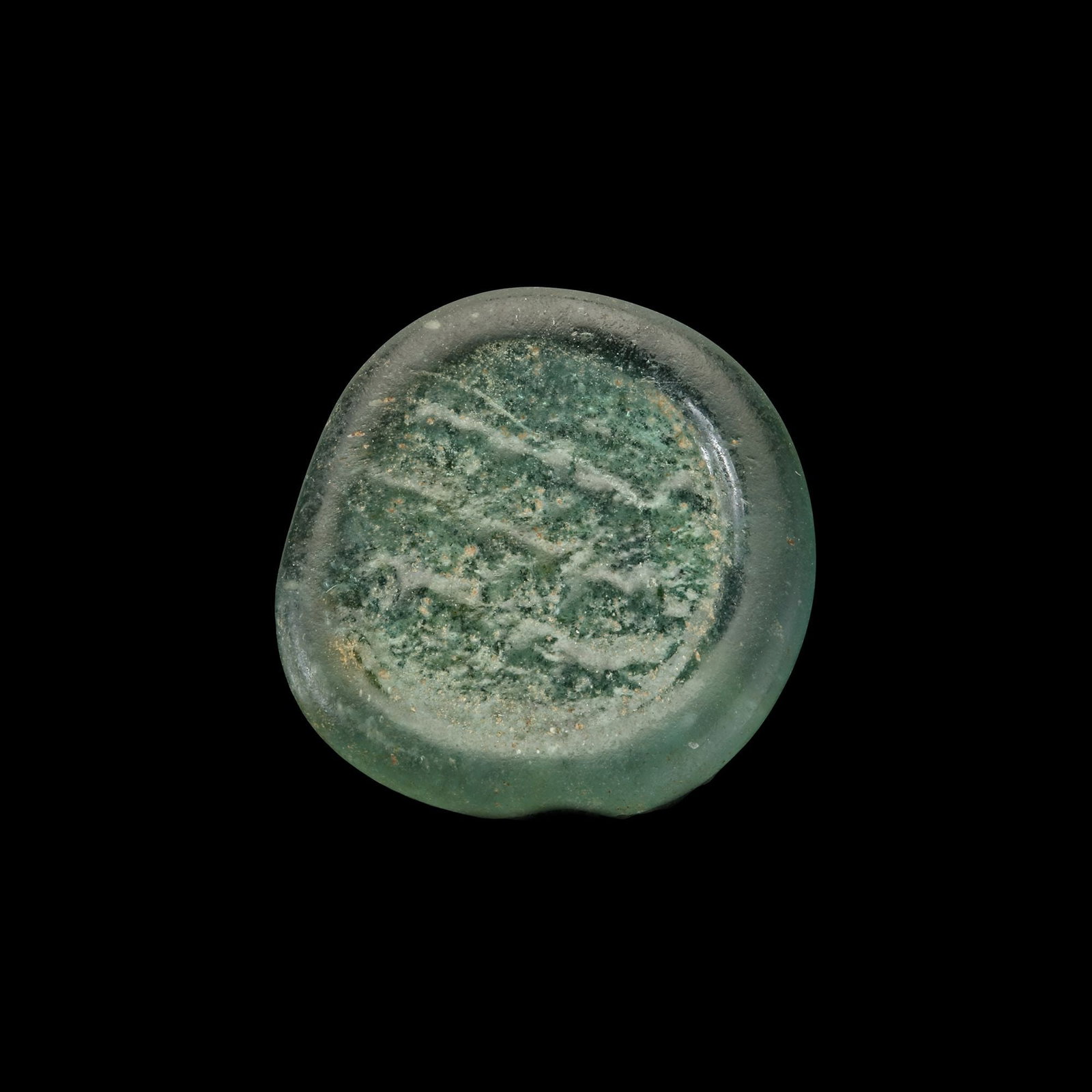 AN EARLY ISLAMIC GLASS WEIGHT OF DIRHAM: Glass weight, moulded and stamped, transparent pale-green in colour, citing in the centre with the name Al-Imam Abu Tamim al-Mustansir Amir al-Mu'mnin (427-487 AH/1036-1094 AD). 2.959 g., 21 mm. coin 
