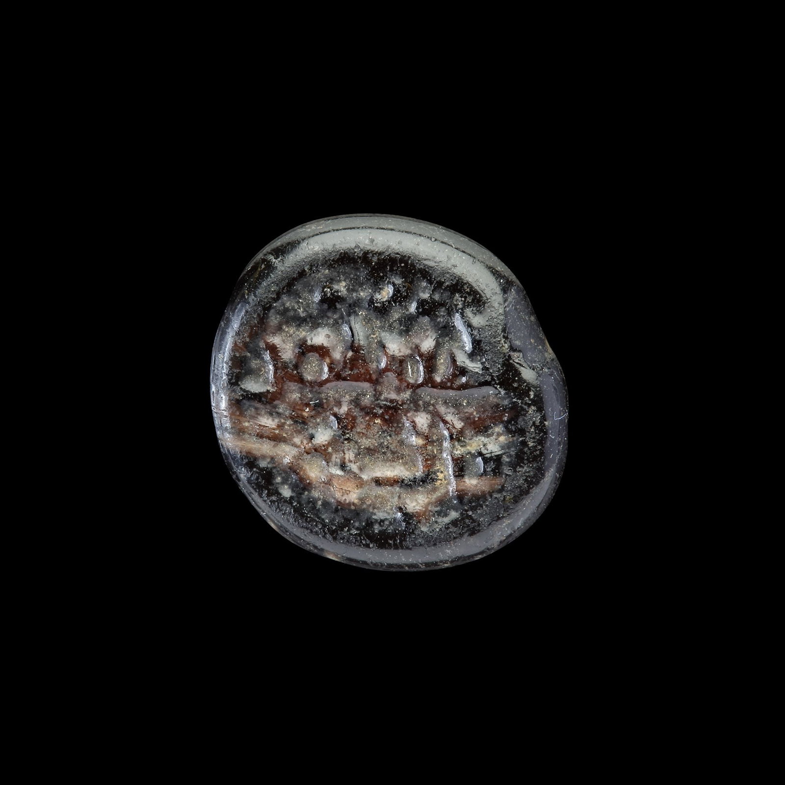 AN EARLY ISLAMIC GLASS WEIGHT OF QUARTER DIRHAM: Glass weight, moulded and stamped, opaque black in colour, citing in the centre with the name al-Mustansir (427-487 AH/1036-1094 AD). 0.752 g., 12 mm. coin weight: quarter dirham. B 284.