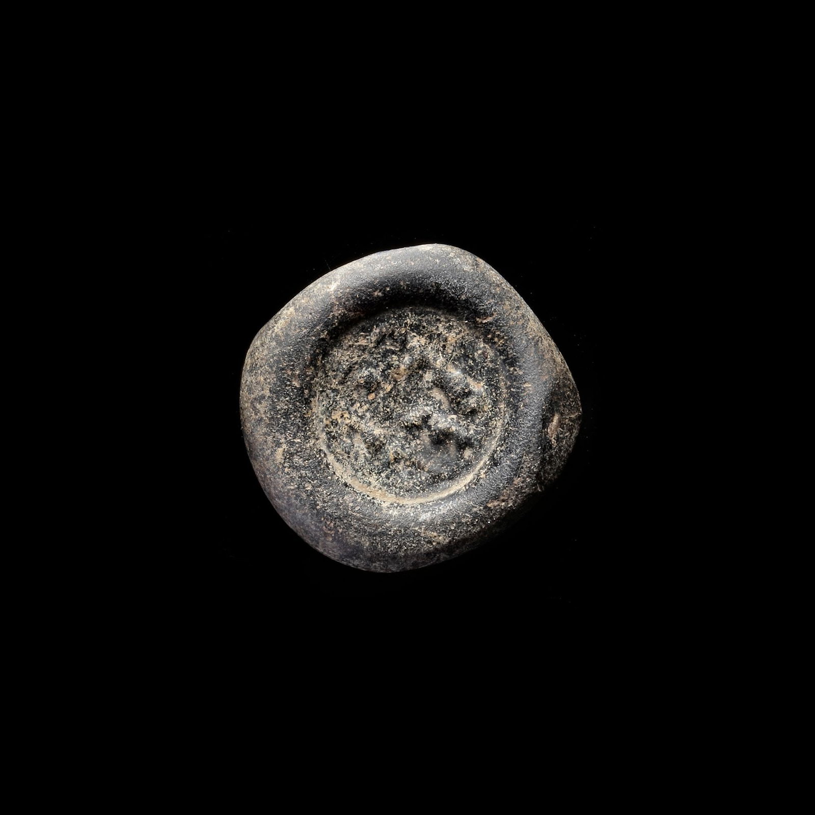 AN EARLY ISLAMIC GLASS WEIGHT OF DOUBLE DIRHAM, 10TH-11TH CENTURY: Glass weight, moulded and stamped, opaque black in colour, citing in the centre with 3 lines of undeciphered Arabic text, 6.040g, 22 mm, coin weight: double dirham.
