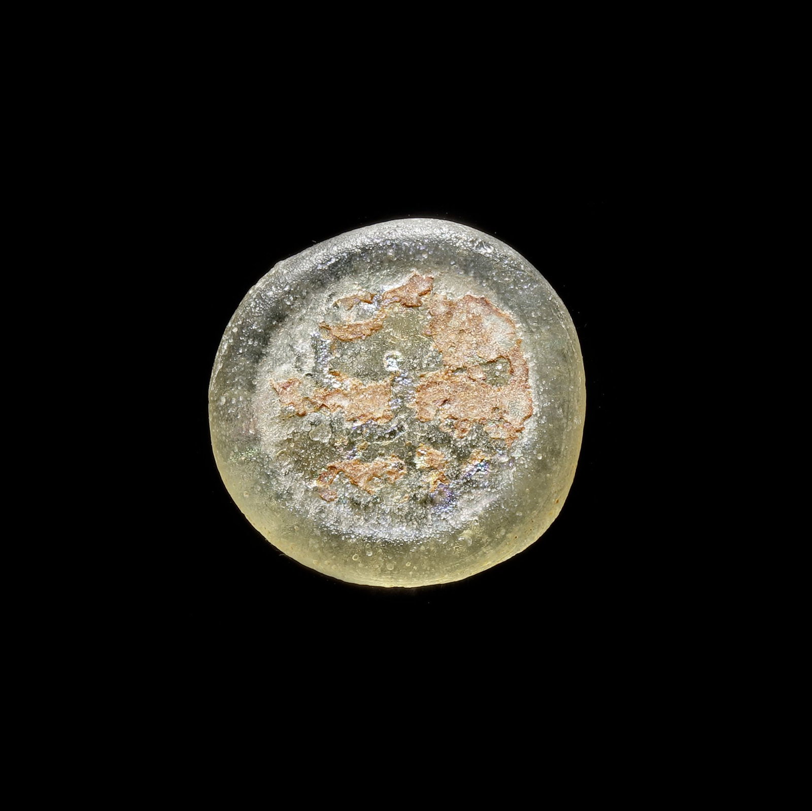 AN EARLY ISLAMIC GLASS WEIGHT OF DOUBLE DIRHAM, 10TH-11TH CENTURY: Glass weight, moulded and stamped, transparent white in colour with splashes, citing in the centre with 2 lines of undeciphered Arabic text. 5.117 g., 24 mm. coin weight: double dirham.