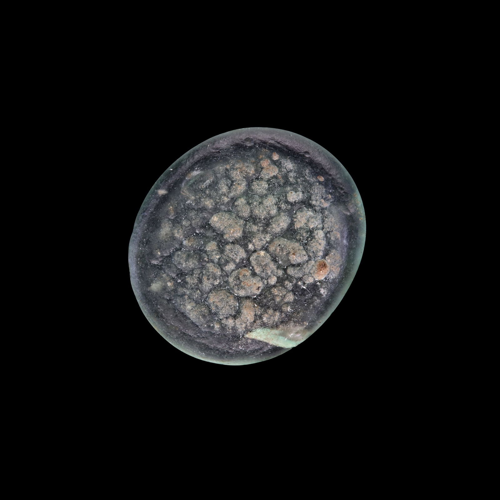 AN EARLY ISLAMIC GLASS WEIGHT OF HALF QUARTER DIRHAM: Glass weight, moulded and stamped, transparent pale-green in colour, citing in the centre with the name AL-Imam Al-Zahir (412-427 AH/1021-1036 AD). 0.337 g., 11 mm. coin weight:1/8 dirham.