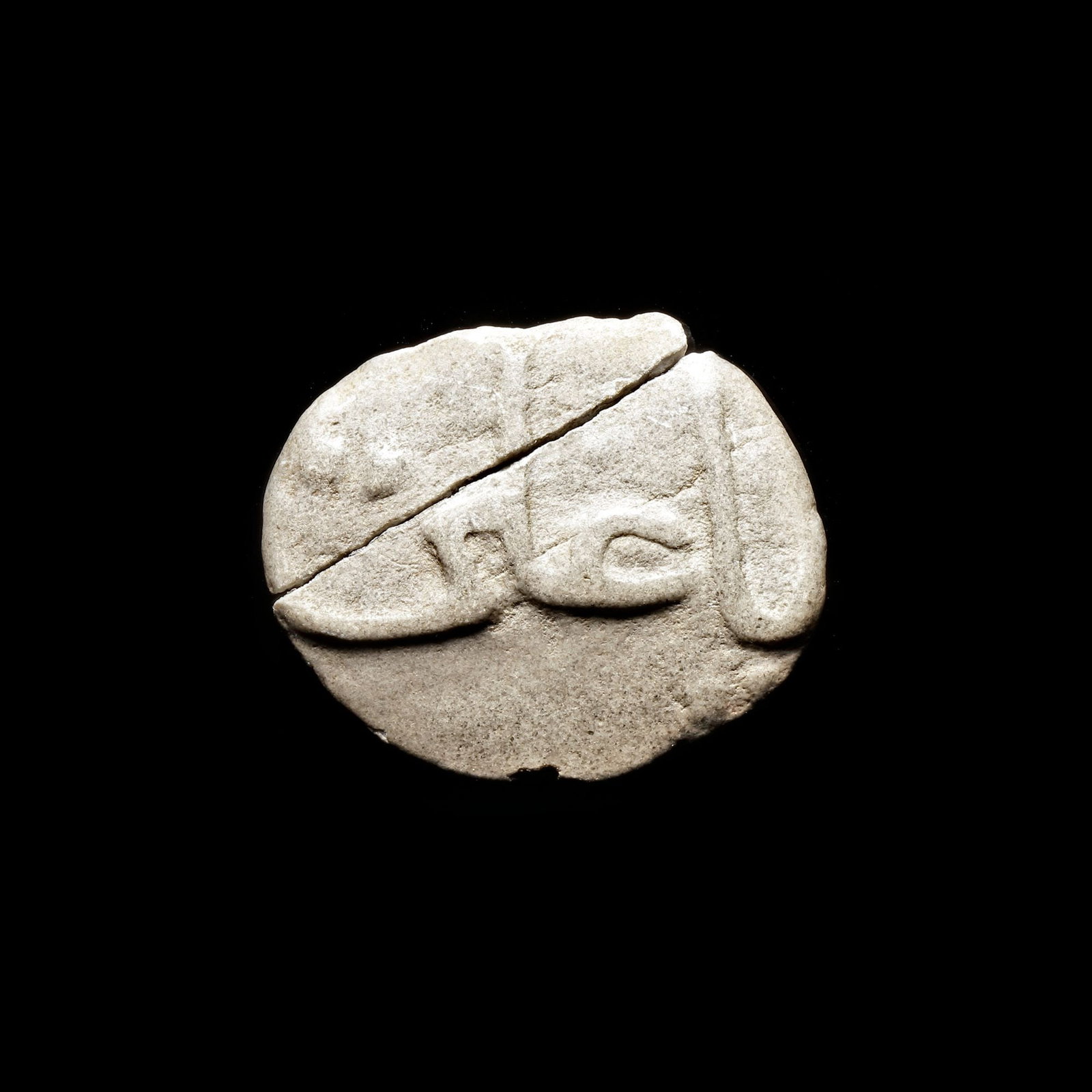 AN EARLY ISLAMIC CLAY AMULET, 10TH-11TH CENTURY: A Fatimid rounded clay, carved on both sides with "Oh Muhammed, Oh Ali' in elegant thuluth script. 9.546 g., 30 by 36 mm.