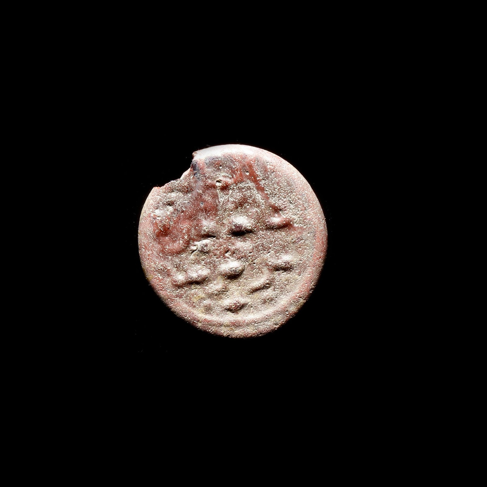 AN EARLY ISLAMIC GLASS WEIGHT OF HALF DINAR: Glass weight, moulded and stamped, opaque copper-red in colour, citing in the centre with the name Al-Zahir Amir- Al-Mu'mnin (412-427 AH/1021-1036 AD). 2.011 g., 18 mm. coin weight: half dinar.
