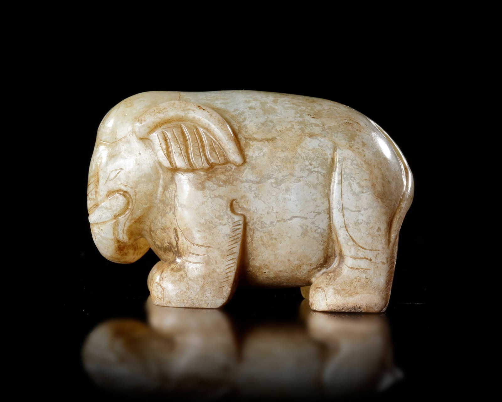 A PALE CELADON JADE ELEPHANT, CHINA, HAN DYNASTY (206 BCâ€“220 AD): A charming pale celadon jade elephant carved in a compact and powerful form, symbolizing strength, wisdom, and prosperity. The sculptor skillfully captured the animalâ€™s gentle character thro