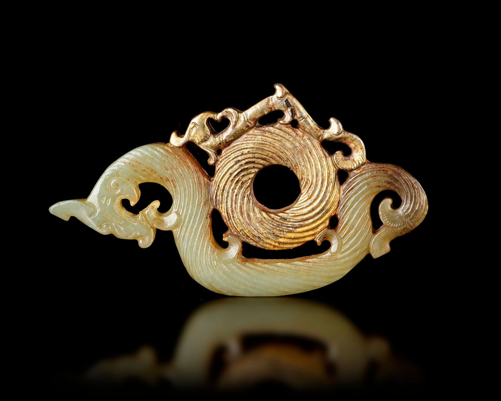 A GREEN JADE AND BRONZE PENDANT, CHINA, SONG DYNASTY (960â€“1279): A finely carved green jade pendant mounted with a bronze element. The soft green jade contrasts beautifully with the warm bronze, highlighting the intricate carving and delicate lines of the design. 9