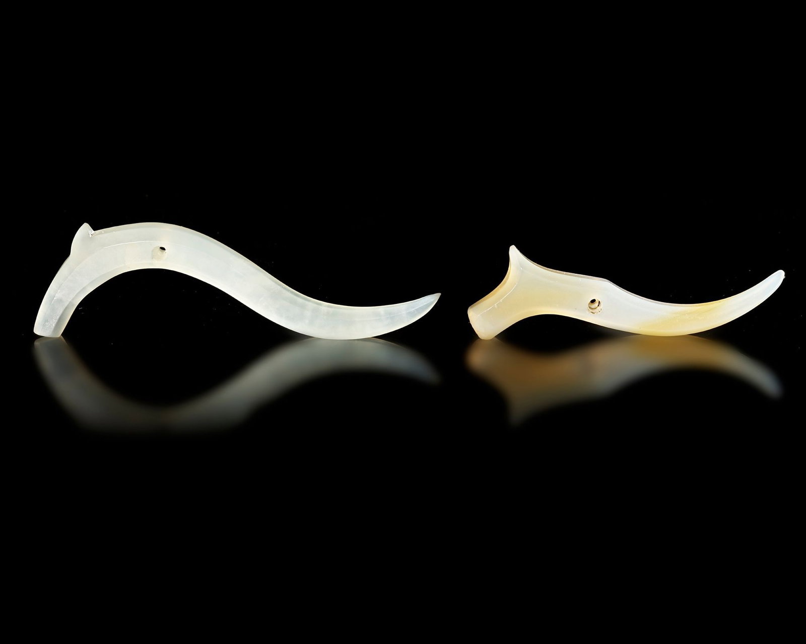 A PAIR OF CELADON JADE S-SHAPED PENDANTS, CHINA, SHANG DYNASTY (CIRVCA 1600-1046 BC): Shang dynasty (c. 1600â€“1046 BC). The smooth curves and minimalistic design highlight the natural translucency and soft green tone of the jade. Small perforations indicate they were likely wo