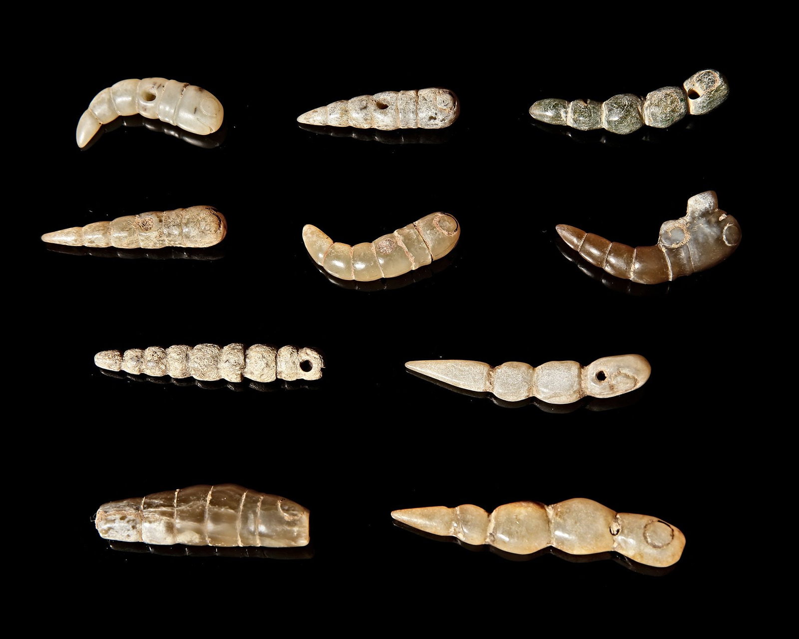 SET OF TEN JADE PENDANTS, CHINA, ZHOU PERIOD (c. 1046â€“256 BCE): A rare set of ten small jade pendants carved in the form of silkworms . Each pendant is finely shaped with segmented bodies and subtle details that capture the natural form of the silkworm. The pieces