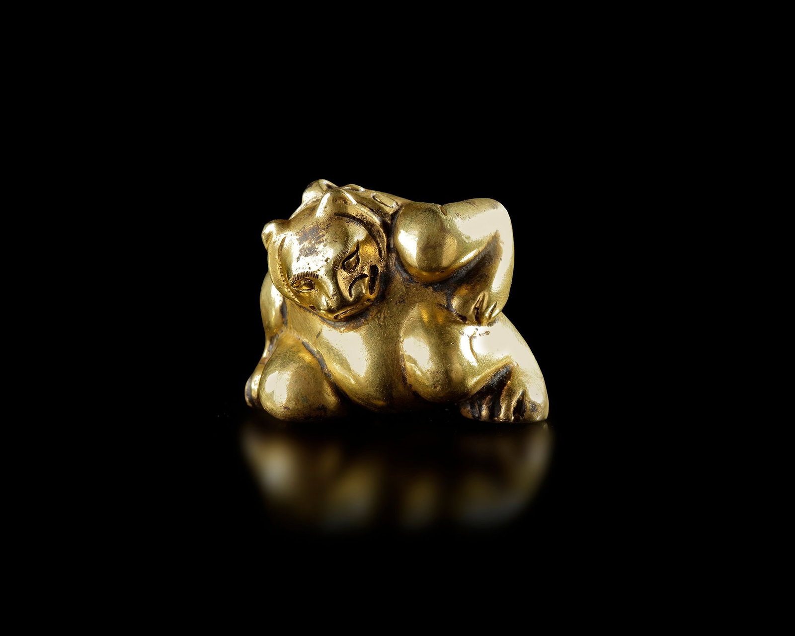 A GILDED BRONZE WEIGHT, CHINA, HAN DYNASTY (206 BCâ€“220 AD): A finely cast gilded bronze weight , sculpted in the form of a reclining animal. The figure is compact and rounded, with delicately incised facial features and stylized limbs, Height: 5 cm Provenance: