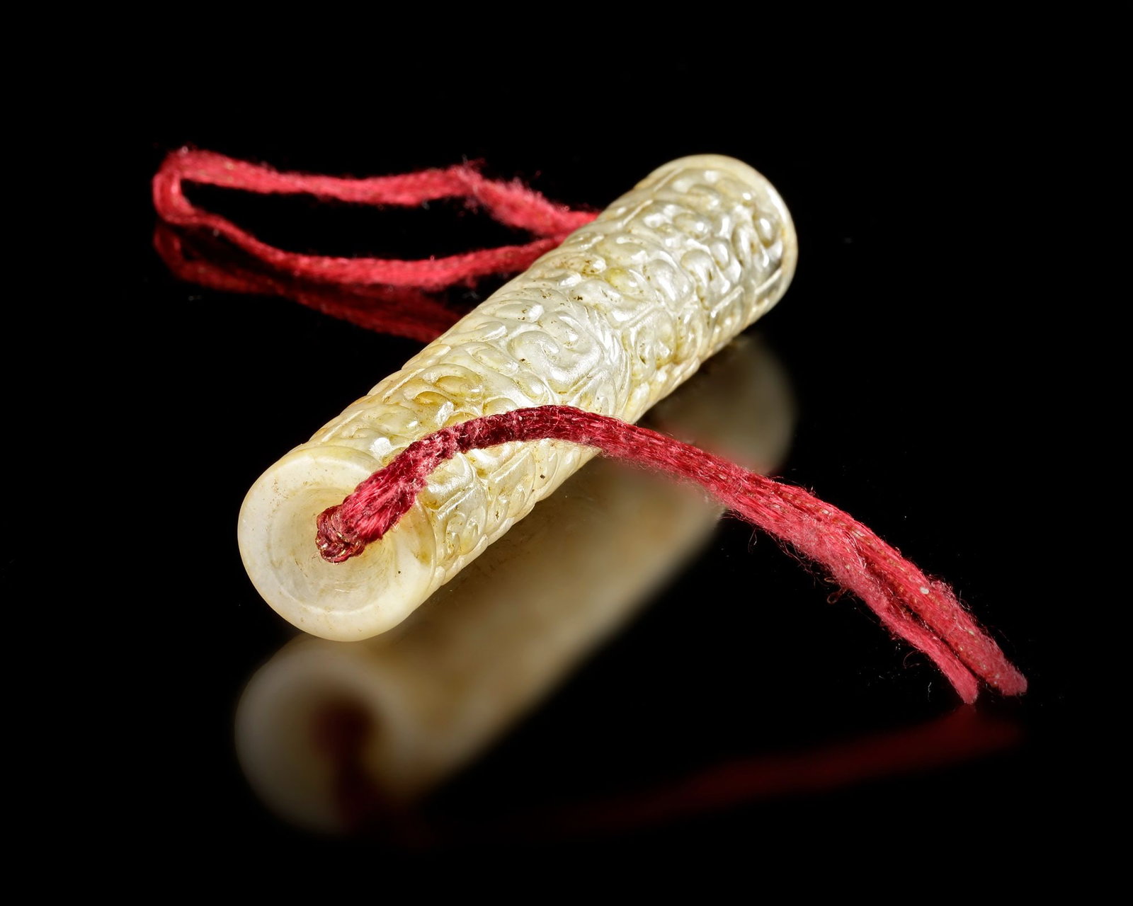 A JADE PENDANT â€?LEâ€?, CHINA, SPRING AND AUTUMN PERIOD (c. 770â€“476 BC): Finely carved tubular jade pendant decorated with continuous archaic scroll and mask motifs. Such pendants were worn as ornaments or ceremonial pieces, reflecting the importance of jade as a symbol of