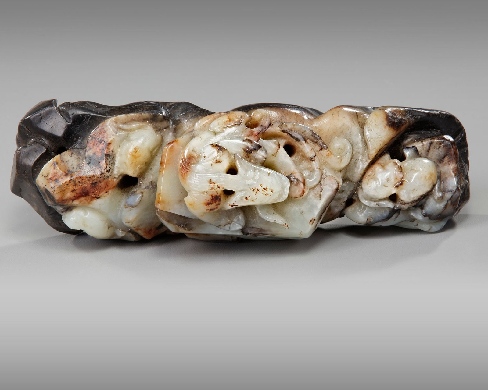 A CHINESE JADE CARVING, 17TH-18TH CENTURY: A Chinese jade carving of a Qilin resting on rocks with three other undefined animals between the rocks. Length 15.5 cm. Provenance: Private collection mr. J.K., Switzerland