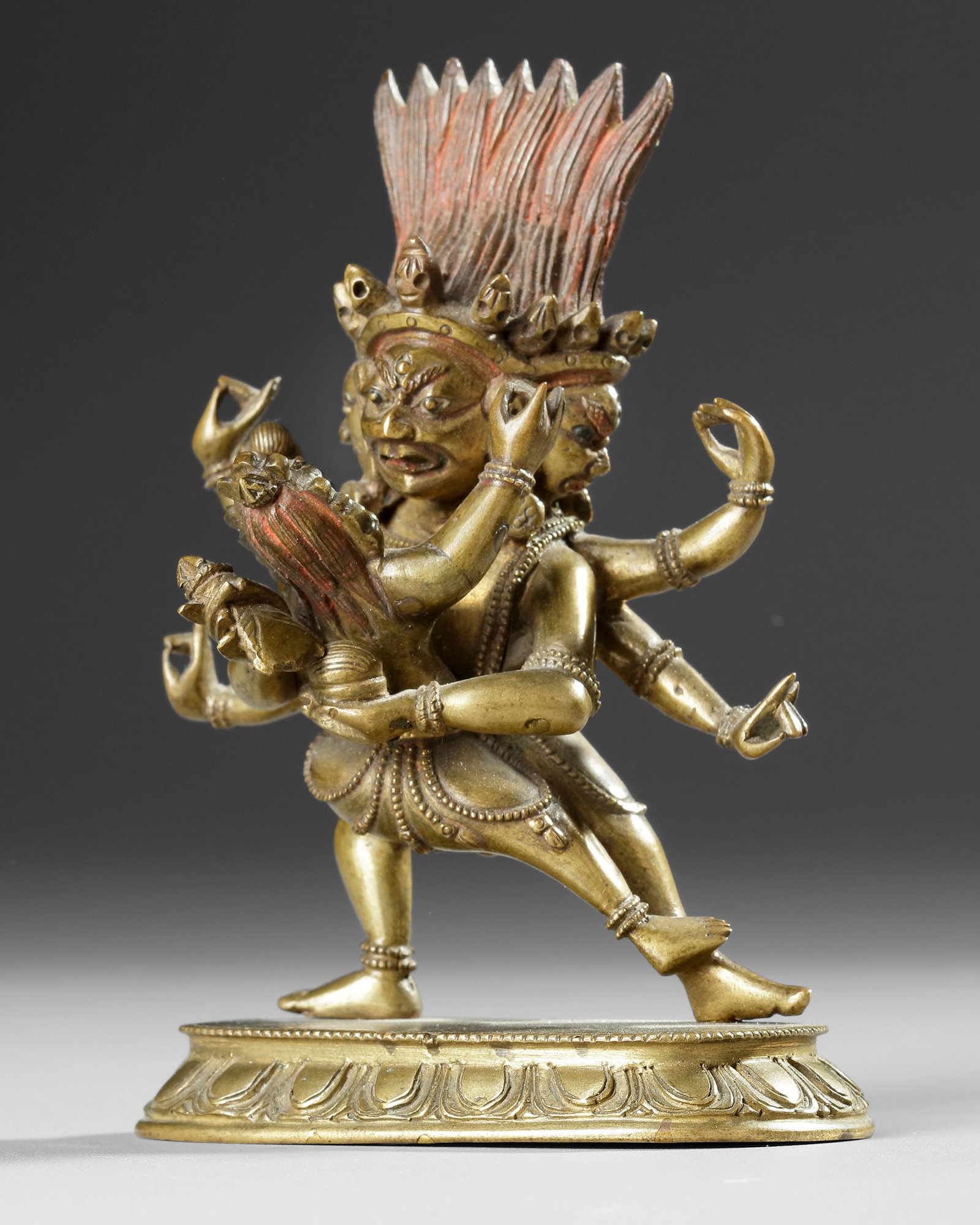 A GILT BRONZE DEITY FIGURE, 19TH CENTURY: A finely cast gilt bronze figure depicted in a dynamic dancing pose with multiple arms and expressive faces. Richly detailed with an elaborate crown, flowing headdress, and ornamental jewelry, the scu