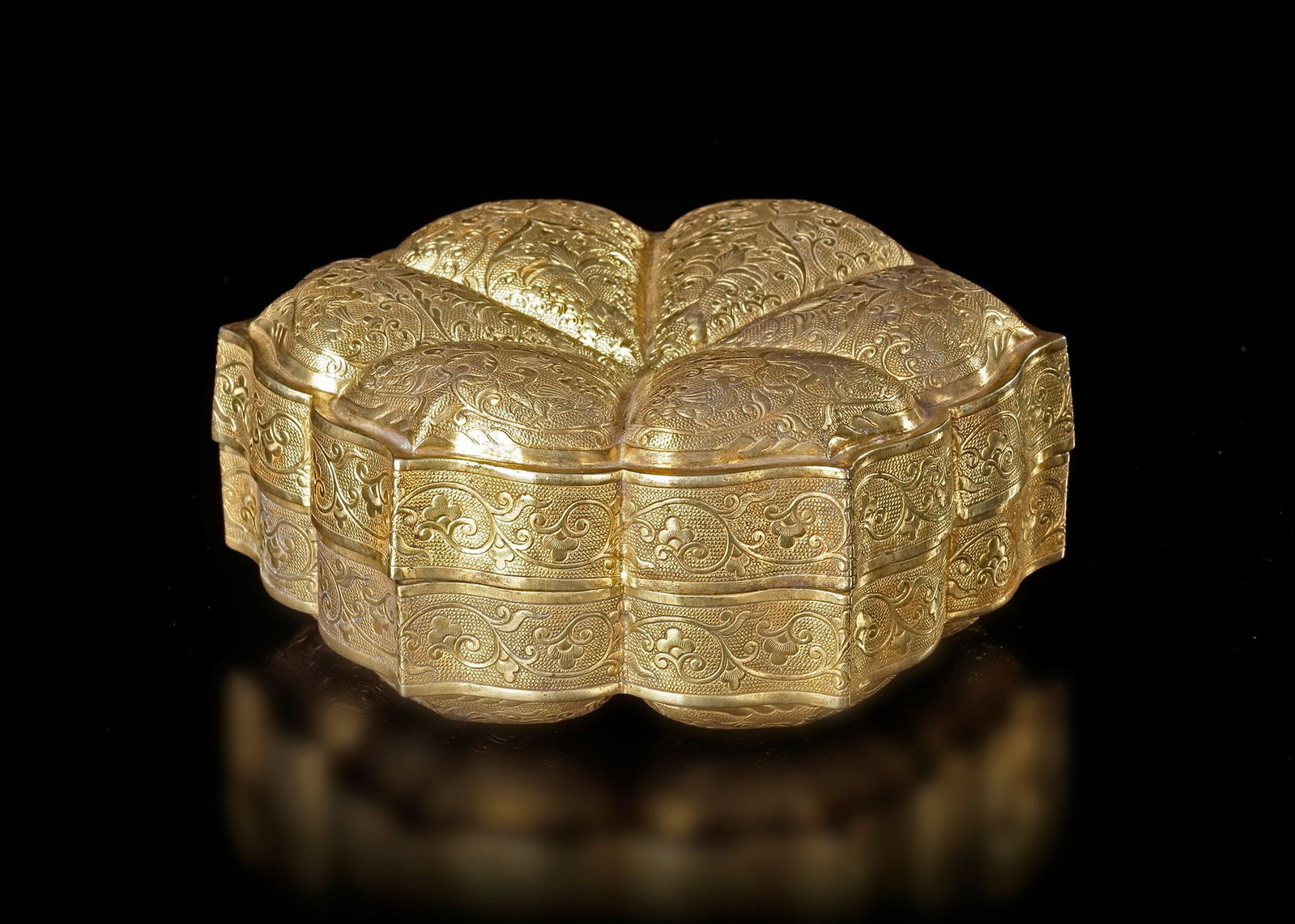 A GILDED BOX MING DYNASTY (1368â€“1644): An elegant gilded box , crafted in a graceful lobed form resembling a lotus flower. The surface is richly decorated with finely engraved scrolling floral and foliate patterns, characteristic of refine