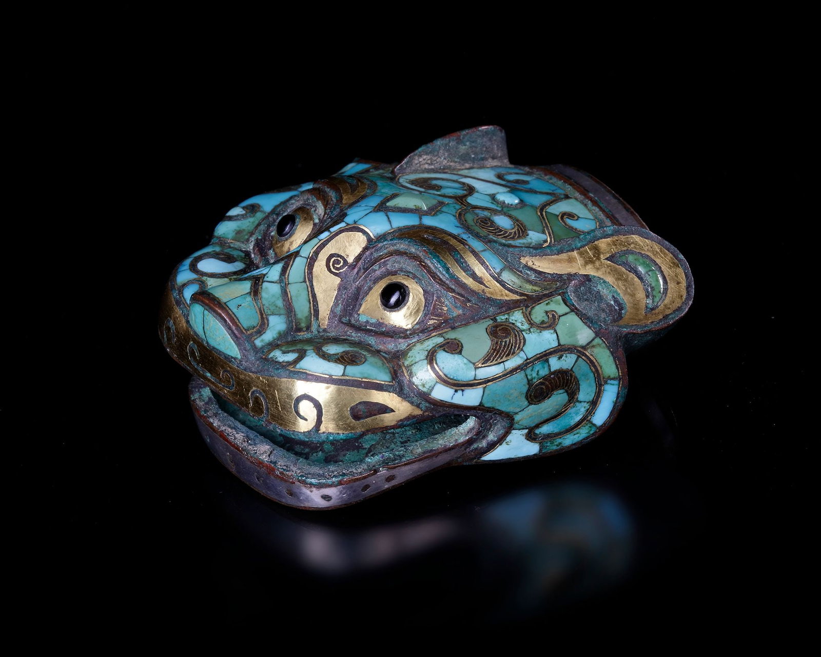 A HAN DYNASTY TIGER HEAD IN TURQUOISE AND GOLD (206 BC â€“ 220 AD): Bronze with turquoise inlay and gold decoration. A striking tiger head ornament , crafted in bronze and richly decorated with turquoise inlay and gold details. The stylized face features large express