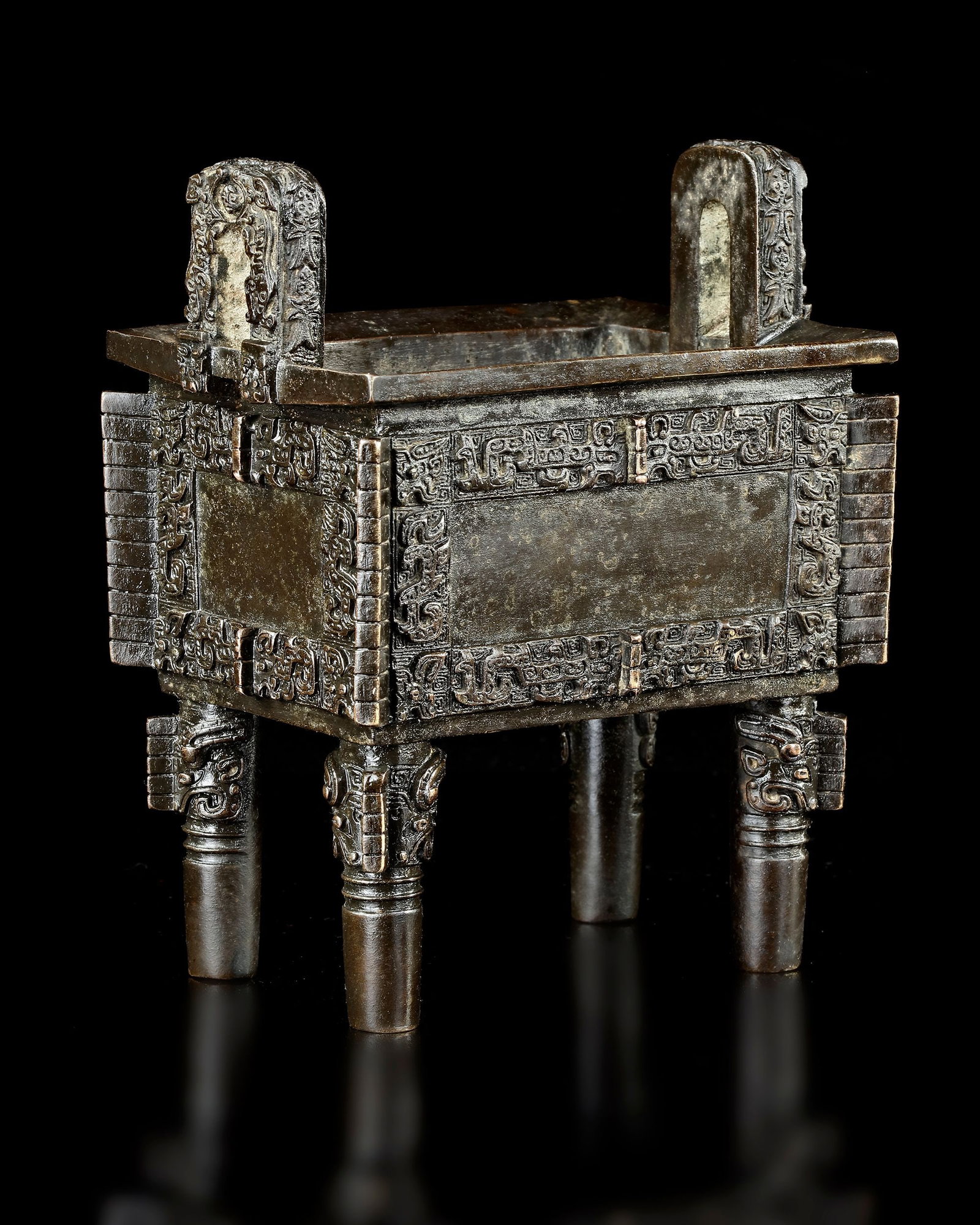 A CHINESE BRONZE CENSER, MING DYNASTY (1368-1644): Chinese archaic bronze rectangular ritual food vessel, cast in relief with a band of bats and leiwen above protruding spikes and hooked corner flanges, the rim set with a pair of high looped handles, 