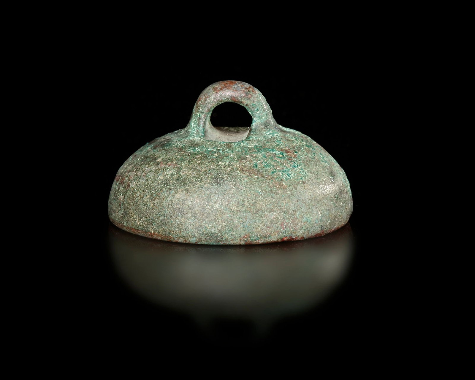 A BRONZE WEIGHT, CHINA, QIN DYNASTY (221 - 206 BC): A small cast bronze weight dating to the , featuring a domed body with a loop handle at the top for easy handling and suspension. The base bears an incised inscription indicating its official standard