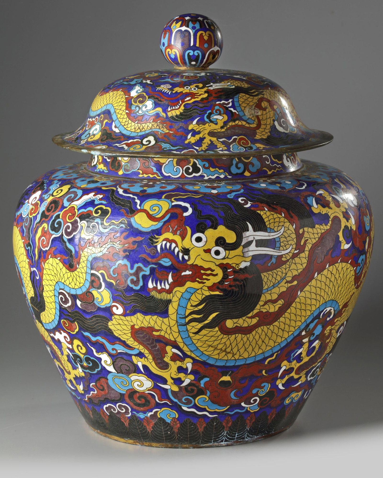 A LARGE CHINESE CLOISONN?‰ ENAMEL â€?DRAGONâ€™ JAR AND COVER,MING DYNASTY (1368-1644): The large vessel is decorated to the exterior with two dragons chasing the flaming pearl amongst flame and cloud scrolls above a stiff leaf band at the foot. The rim is marked with an apocryphal Xuand