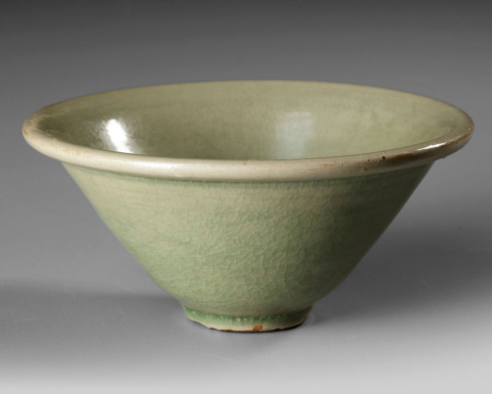 A CHINESE LONGQUAN CELADON BOWL,MING DYNASTY (1368-1644): A Chinese porcelain bowl with gently flaring sides rising from a short foot to an everted rim, covered overall in a thick sea-green glaze, the base left unglazed. Diameter: 10.5 cm Height: 5 cm.