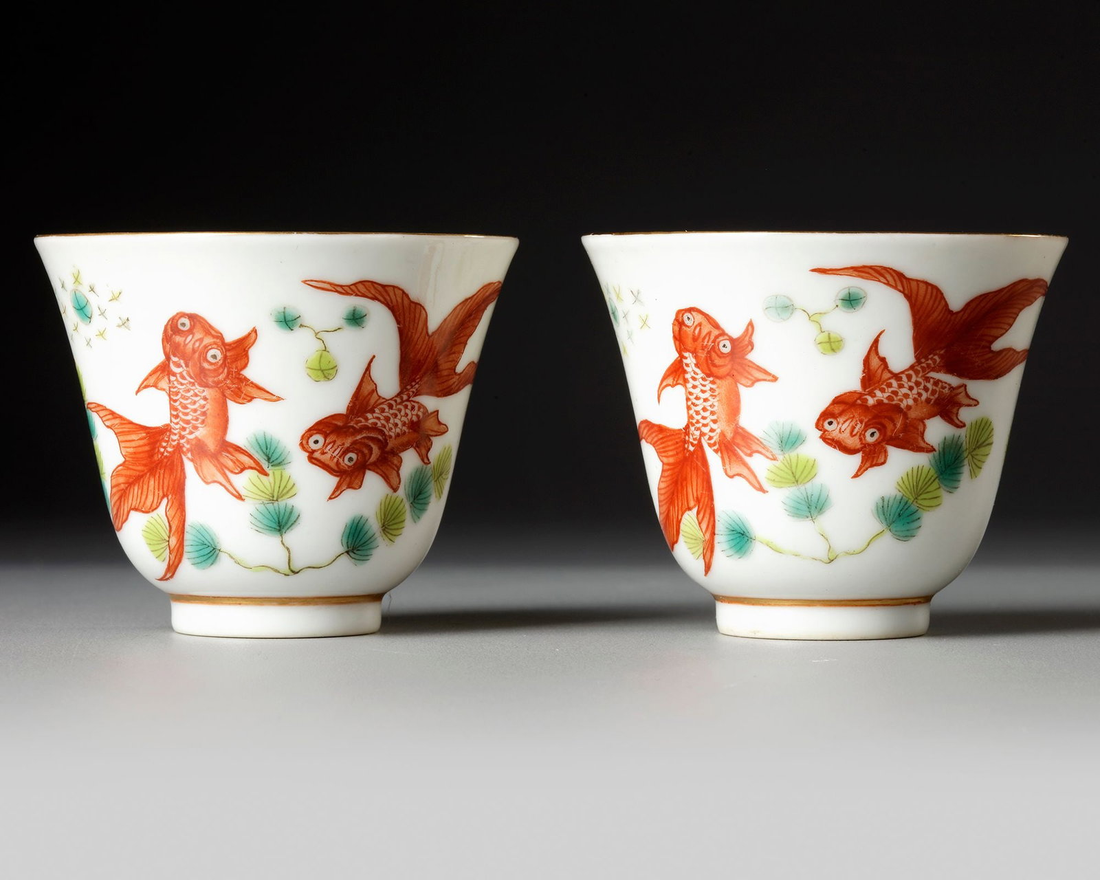 A PAIR OF CHINESE FAMILLE VERTE 'GOLDFISH' TEACUPS, 20TH CENTURY: The teacups are decorated with water-plants, goldfish and gilt to the rim and top of the foot. Diameter: 6 cm.