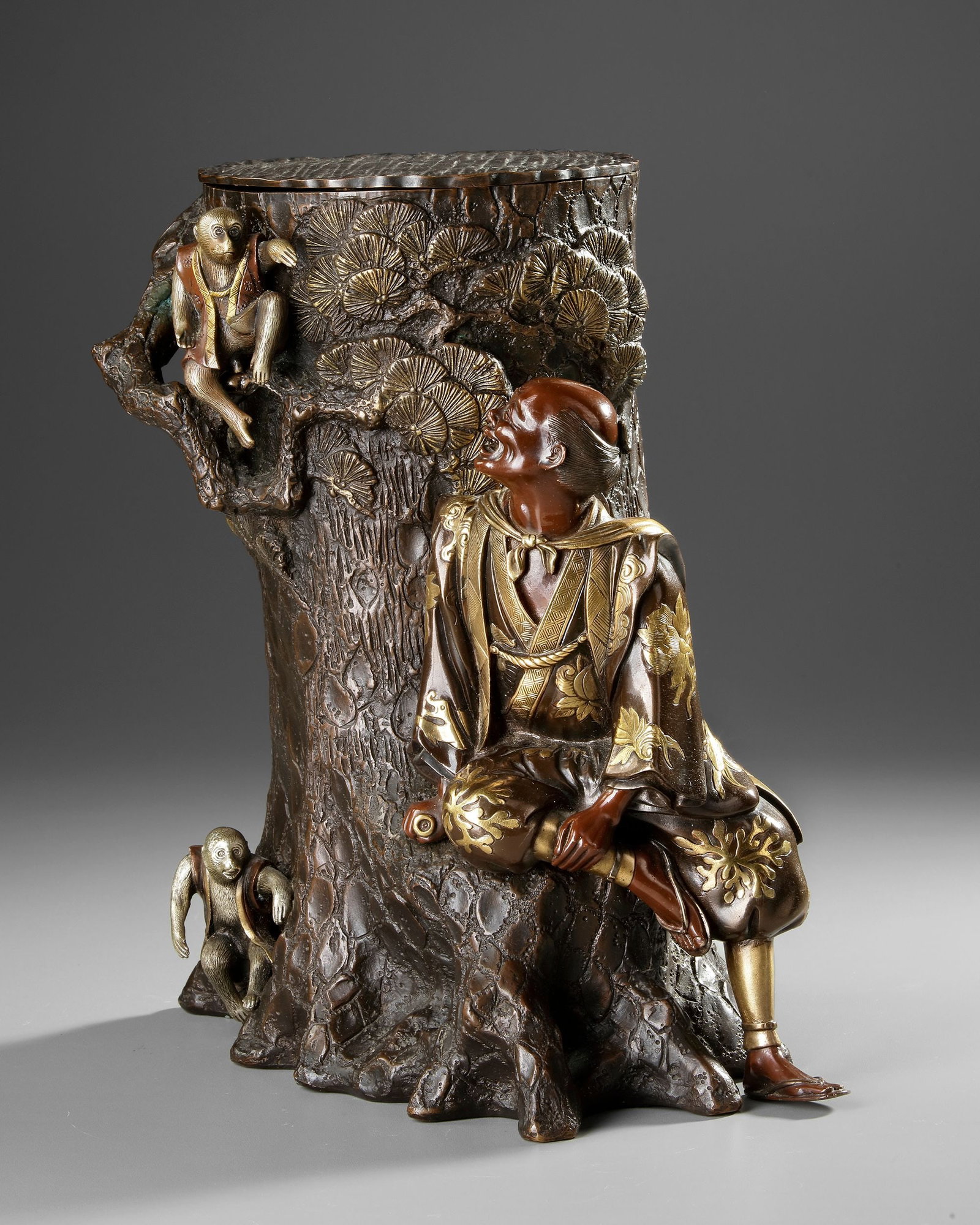 A LARGE JAPANESE BRONZE AND GILT FIGURAL SCULPTURE, MEIJI PERIOD (1868-1912): A fine gilded bronze sculpture of a man sitting on the side of a tree playing with two monkeys. Inside the tree is a removable vase. Height 36.5 cm.