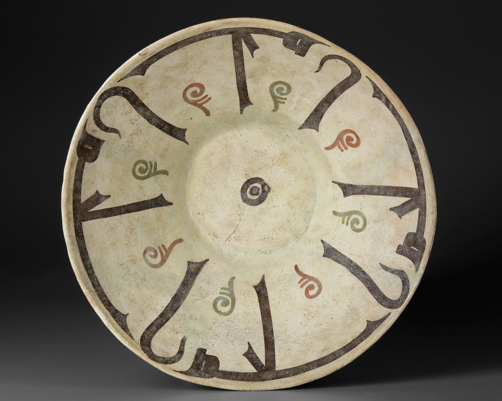 A NISHAPUR CALLIGRAPHIC POTTERY BOWL, PERSIA, 10TH CENTURY: A bowl of truncated conical form with steep flaring walls set on a low, slightly everted foot. The interior is decorated in black with a radial band of Kufic script running below the rim, arranged in 
