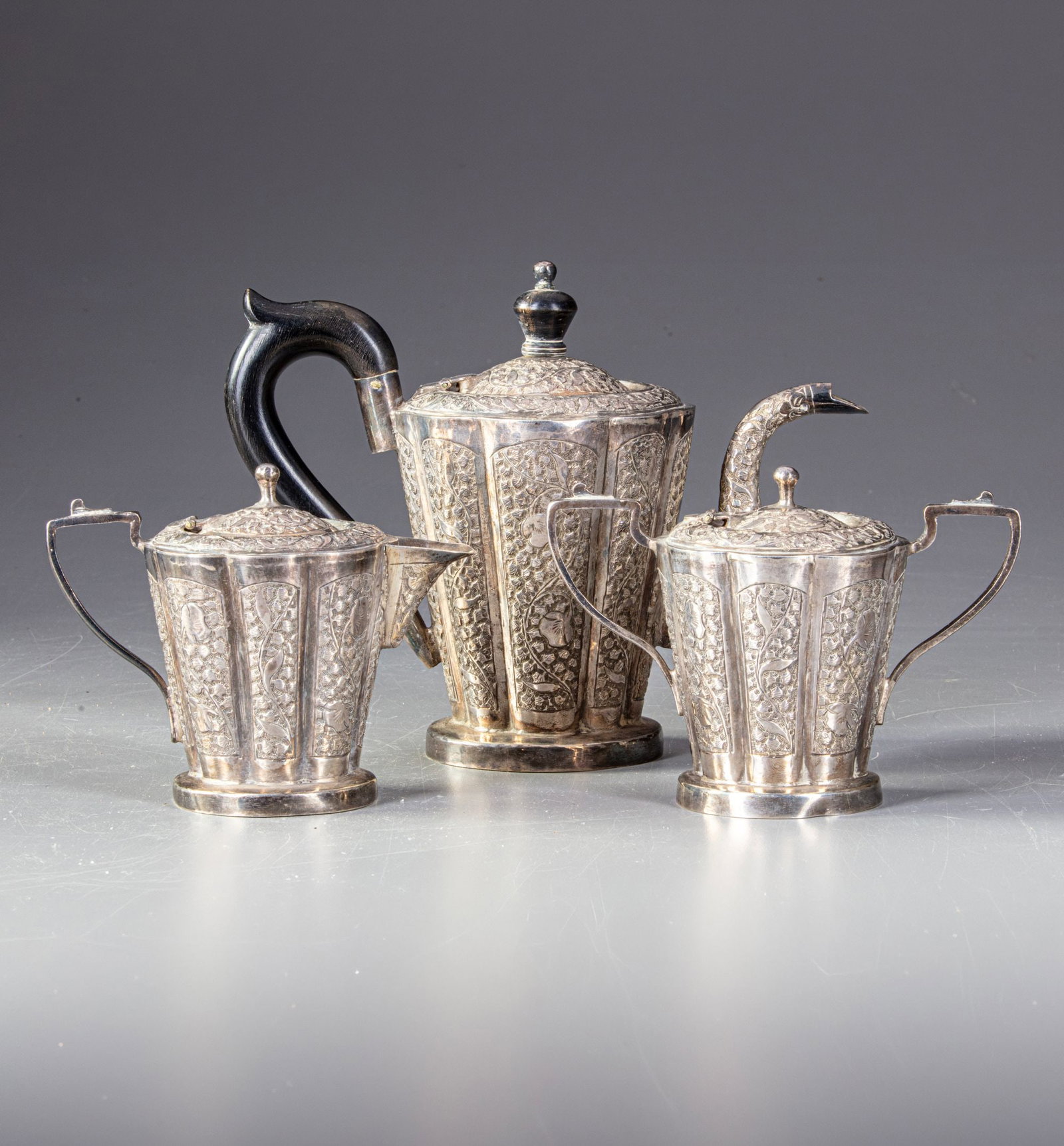 A PERSIAN SILVER TEA SET, 19TH CENTURY: Comprising a teapot, sugar bowl, and milk jug. Each piece is finely crafted with intricate openwork floral and vine patterns. 1}15 by 20 cm. 271gr. 2}14 by 10 cm. 145gr. 3}13 by 10 cm. 137gr. THE