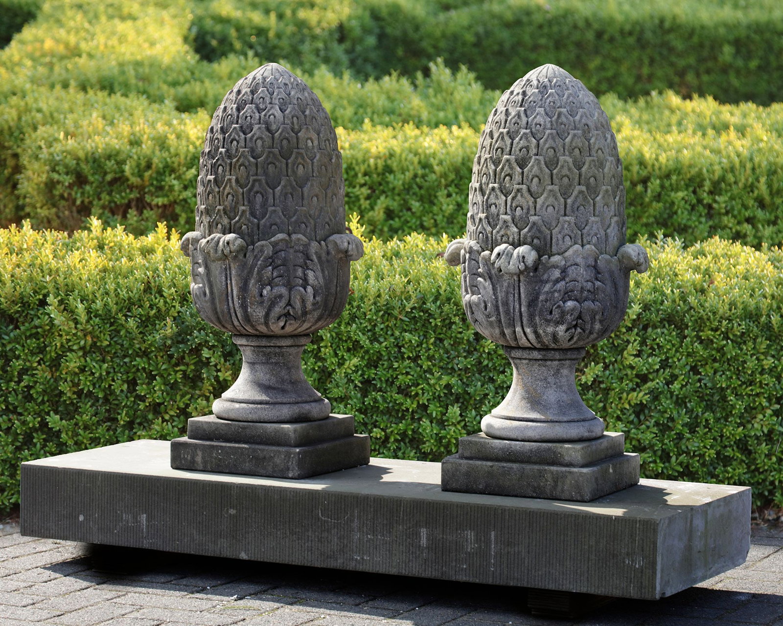 A PAIR OF CARVED LIMESTONE PIER FINIALS, 20TH CENTURY: Height 80 cm. Plinth 30 by 30 cm.