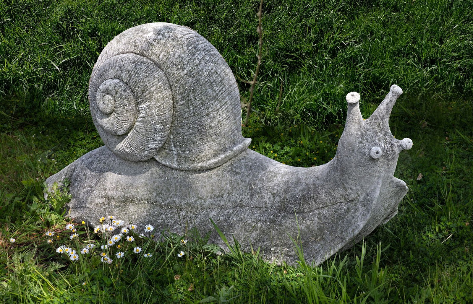 A VERY LARGE LIMESTONE SCULPTED MODEL OF A GARDEN SNAIL: Modelled with head raised and tentacles out. Height 52 cm. Long overall 118 cm.