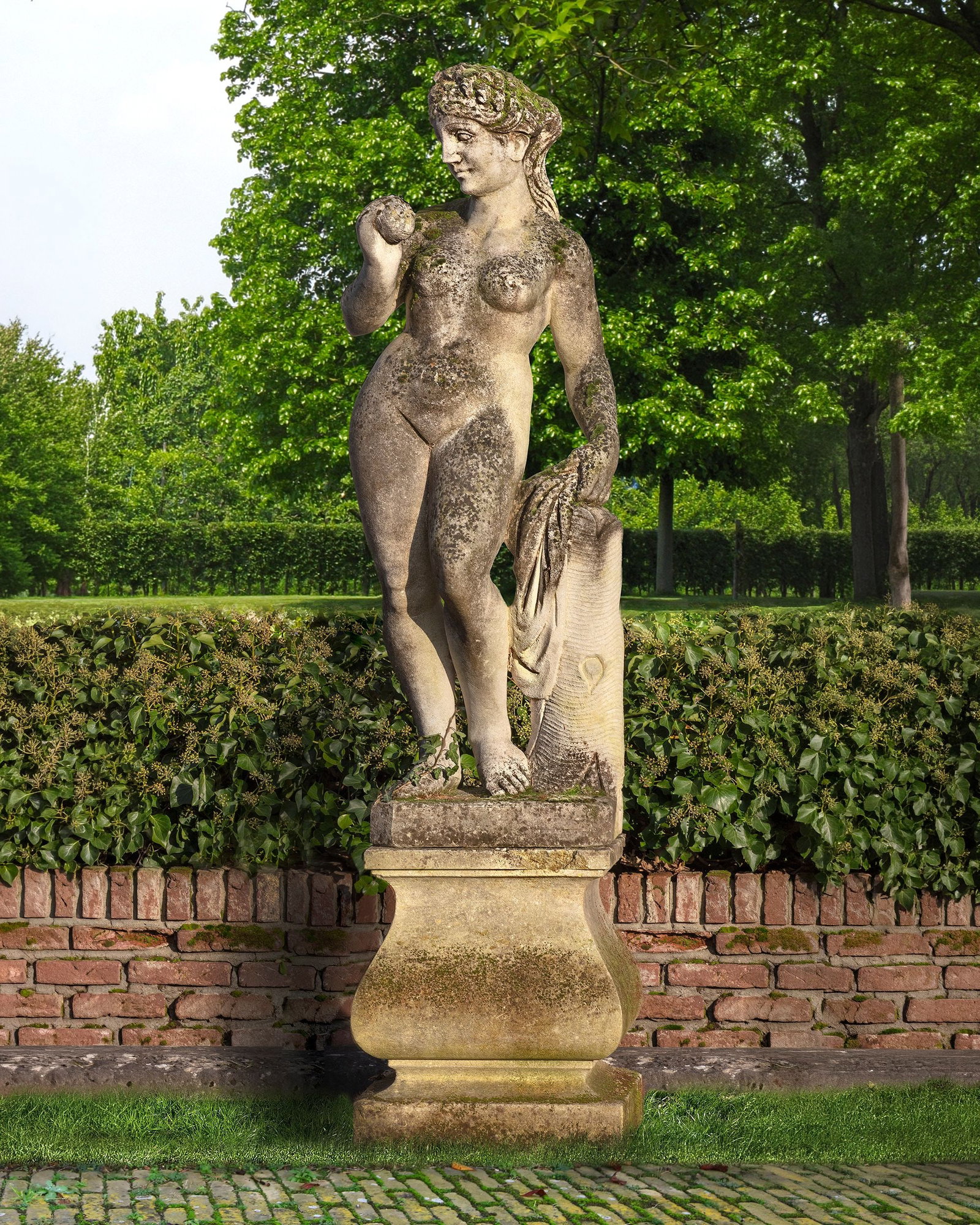 A SCULPTED LIMESTONE MODELS REPRESENTING VENUS, EACH FIRST QUARTER 20TH CENTURY: Portrayed standing and nude, holding an apple aloft in her right hand and her drapes in her right, leaning nonchalantly against a tree-stump. Atop a square section baluster pedestal, height 59 cm. squ