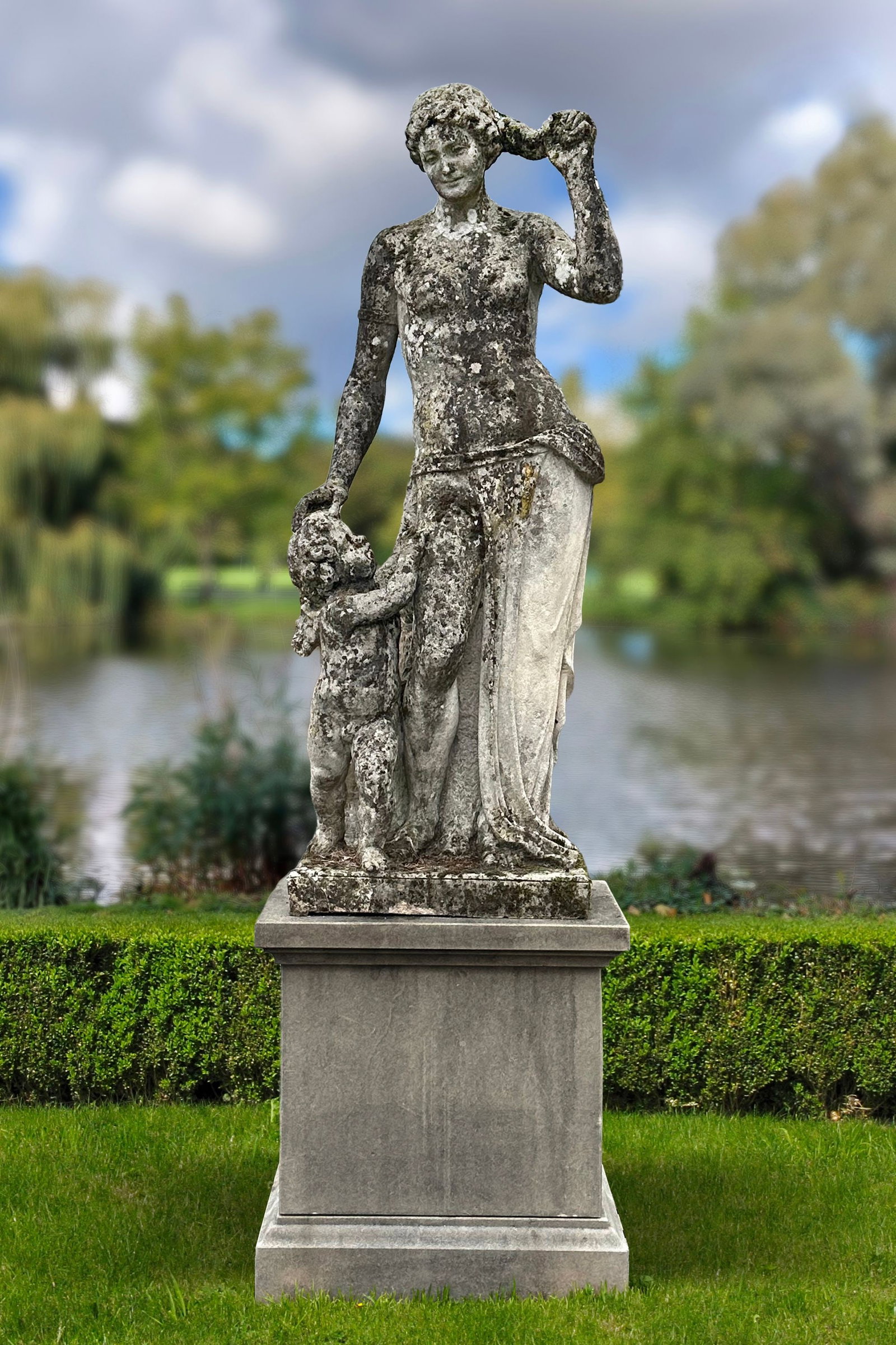 A CARVED LIMESTONE MODEL OF A MOTHER WITH CHILD, 19TH CENTURY: This classical female figure is portrayed with a child leaning against her leg and looking upwards. The child holds something in his hand, possibly an attribute related to water or love, which is comm