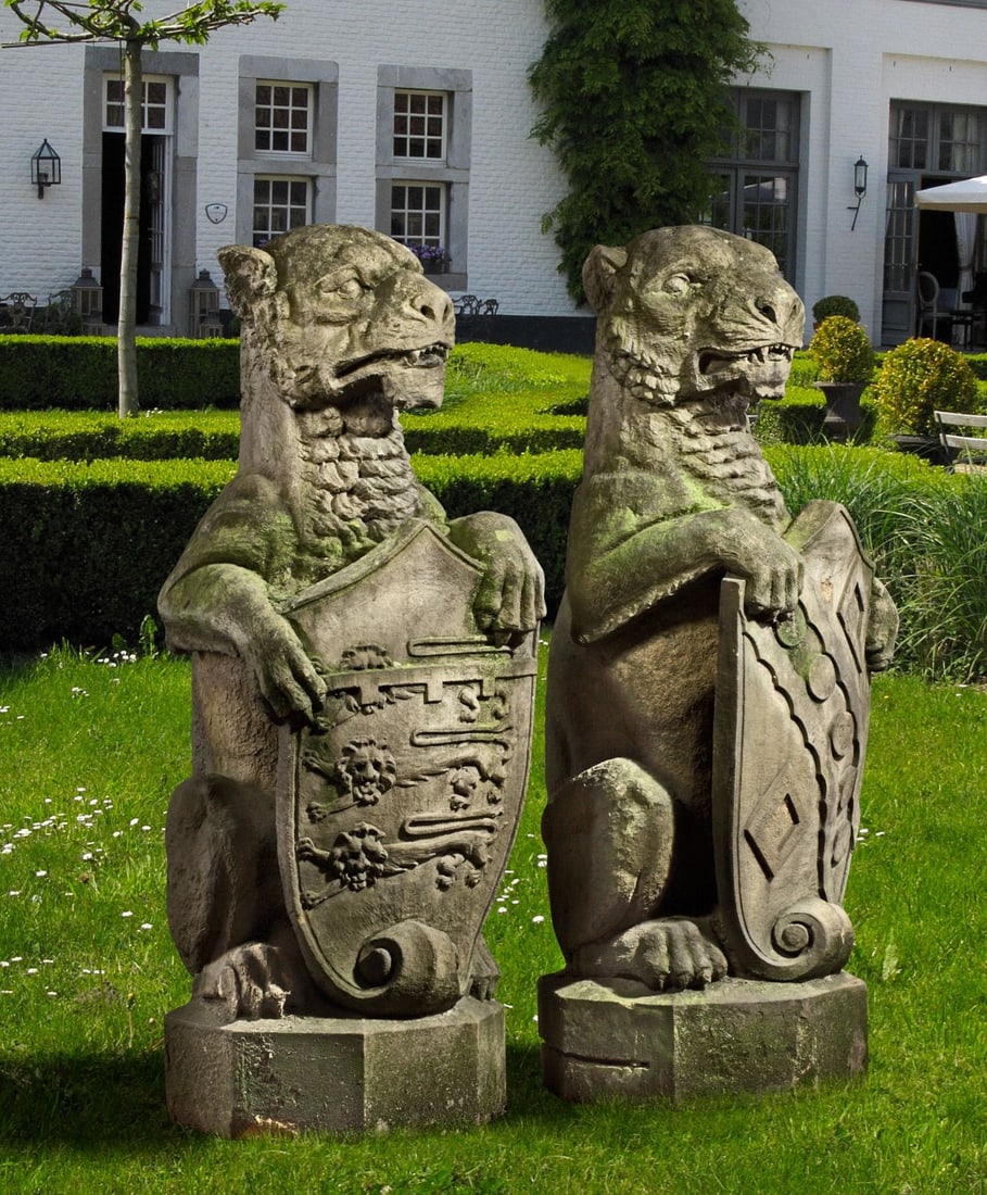 A PAIR SCULPTED SANDSTONE PIER FINIALS CARVED AS HERALDIC LIONS ALMOST CERTAINLY ENGLISH, 19TH: The beasts each portrayed sejant, each with forepaws supporting a shield, on octagonal bases. Height 124 cm.
