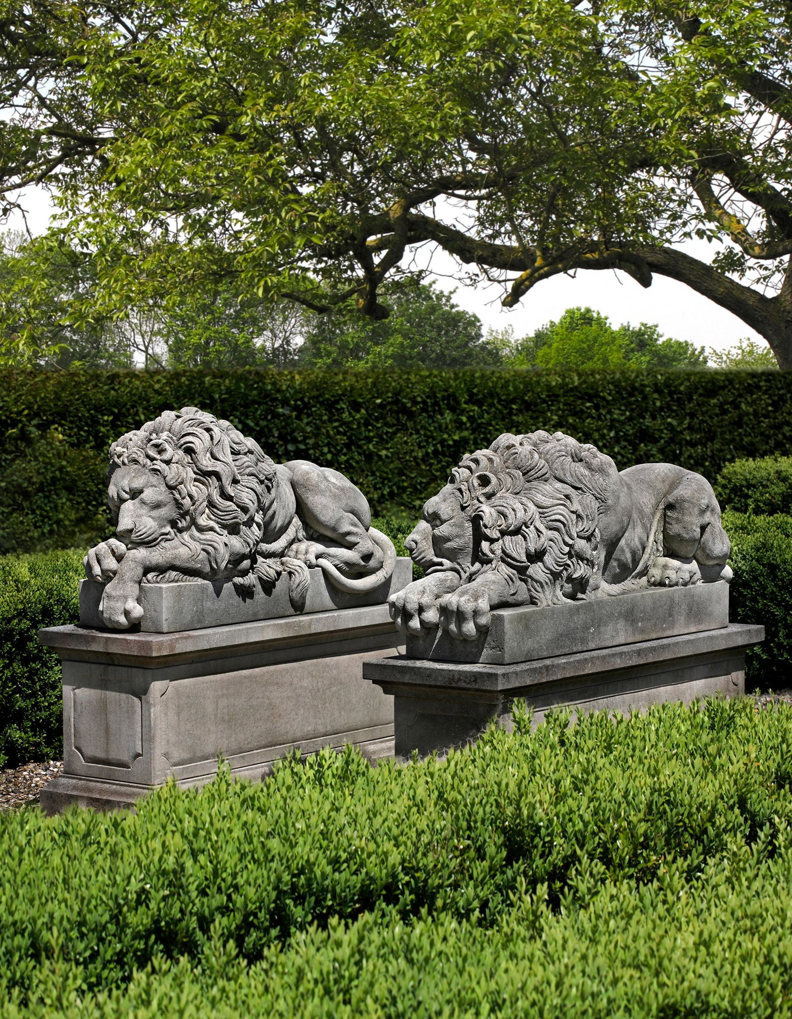 A PAIR OF SCULPTED LIMESTONE MODELS OF RECUMBENT LIONS, SECOND HALF 20TH CENTURY, AFTER ANTONIO: Each typically portrayed with forepaw resting above the other, on integrally carved rectangular pedestals. Height each 65 cm. Atop rectangular section pedestals, each height 55 cm., length 137 cm., wi