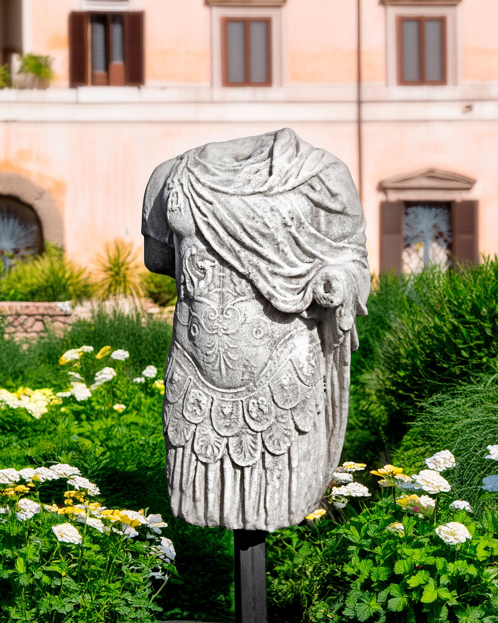 A SCULPTED MODEL OF A TORSO OF A ROMAN WARRIOR, 20TH CENTURY: The torso set on a supporting pole on iron plate. Height overall 140 cm.