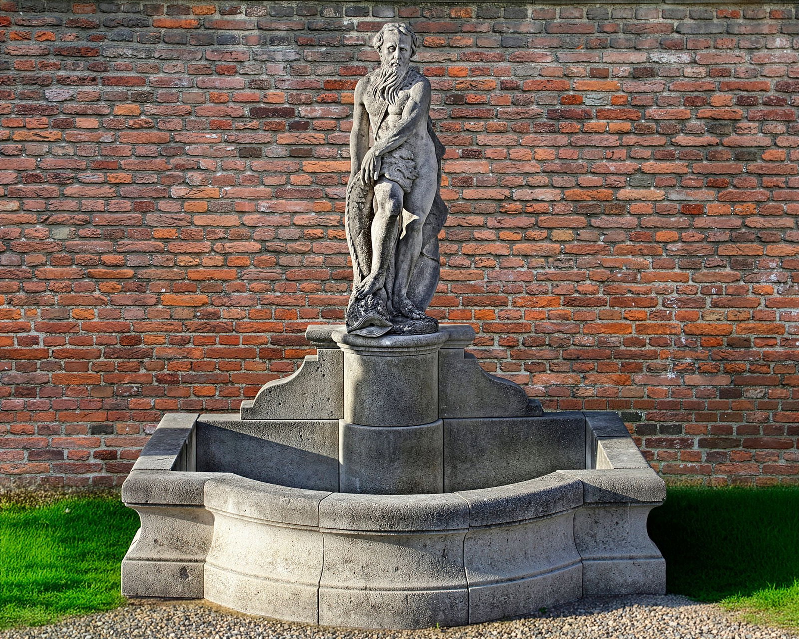 A SCULPTED LIMESTONE FIGURAL WALL FOUNTAIN, SECOND HALF 20TH CENTURY: The figure, possibly Neptune, portrayed nude and standing above a dolphin, the water issuing from the beastâ€™s agape mouth, above a raised plinth and concave moulded pool surround. Height of 