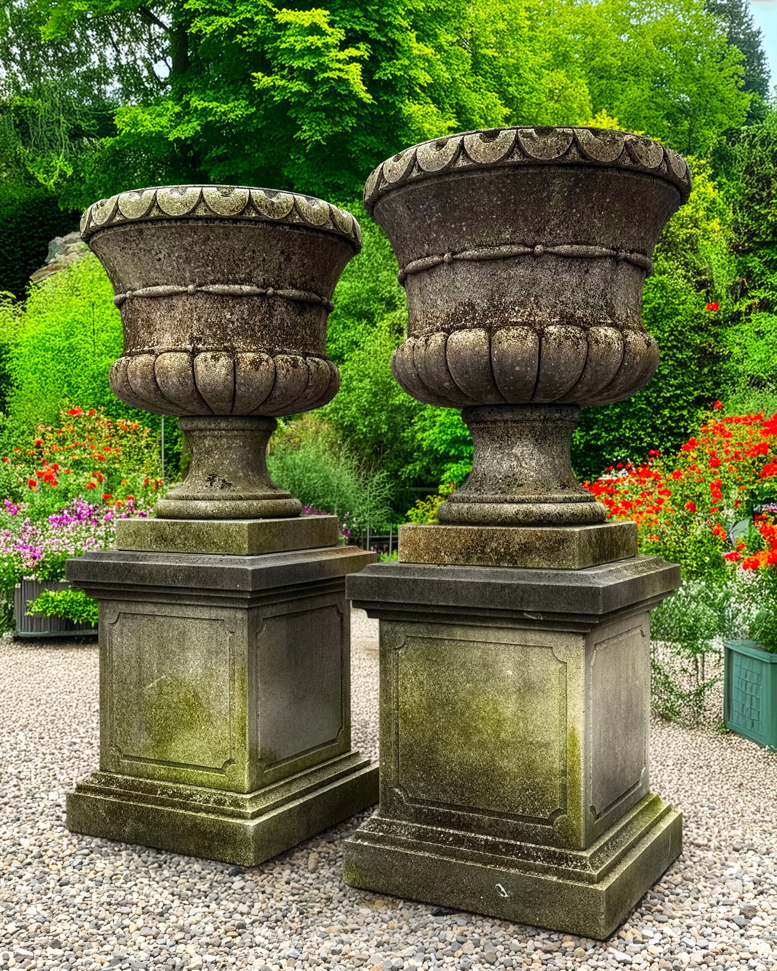 A PAIR OF CARVED LIMESTONE PLANTERS, 20TH CENTURY: Each with an everted rim and raised 'ring' decoration to the body above the lobed underside, and square pedestal. Height 65 cm. Diameter 60 cm. Height overall 125 cm.