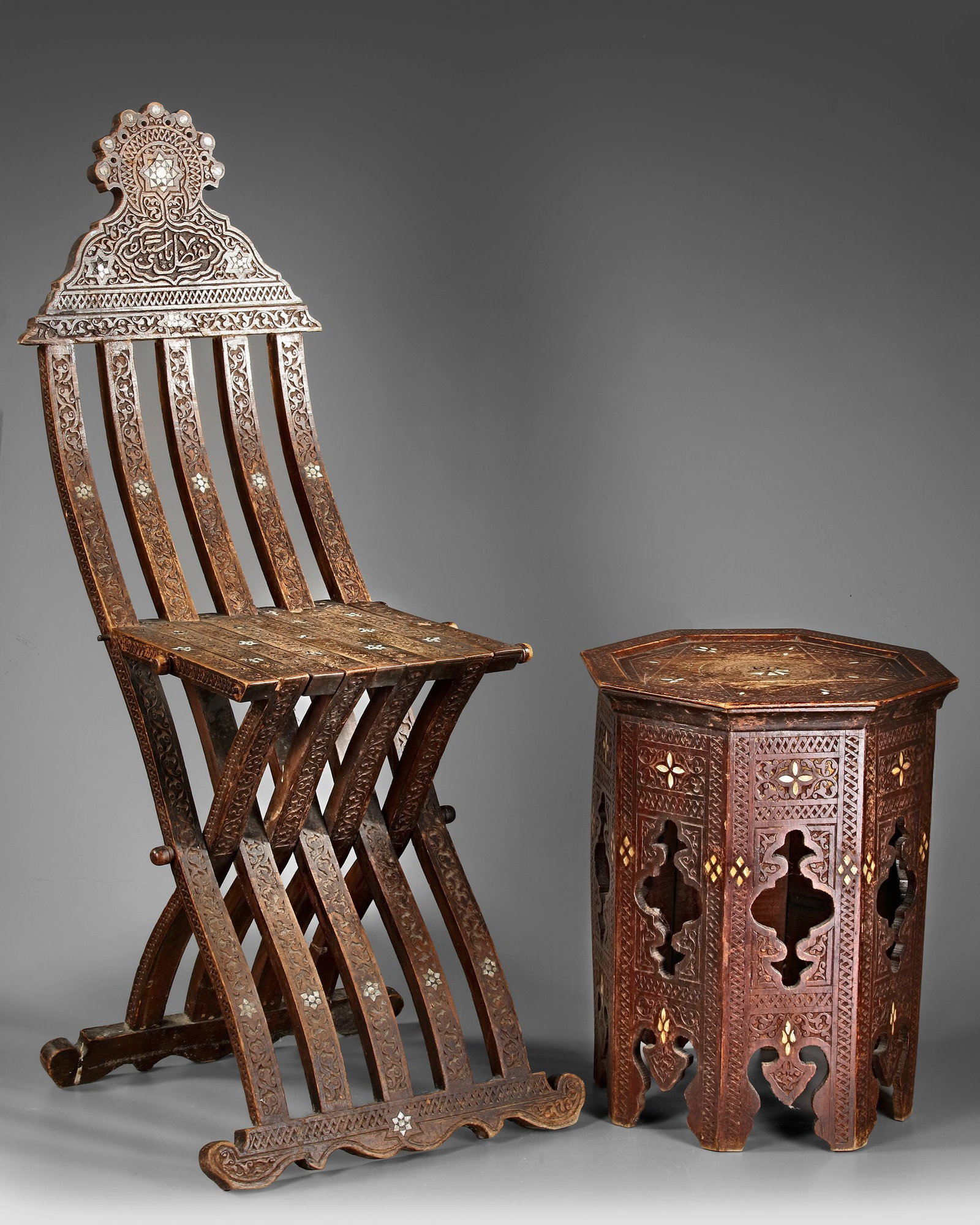 A DAMASCUS MOTHER OF PEARL-INLAID WOOD FOLDING CHAIR, SYRIA, LATE 19TH CENTURY: Carved in relief with palmettes and inlaid in mother of pearl with floral motifs. 103 by 45 by 35 cm. Two knobs on the left side of the seat missing.