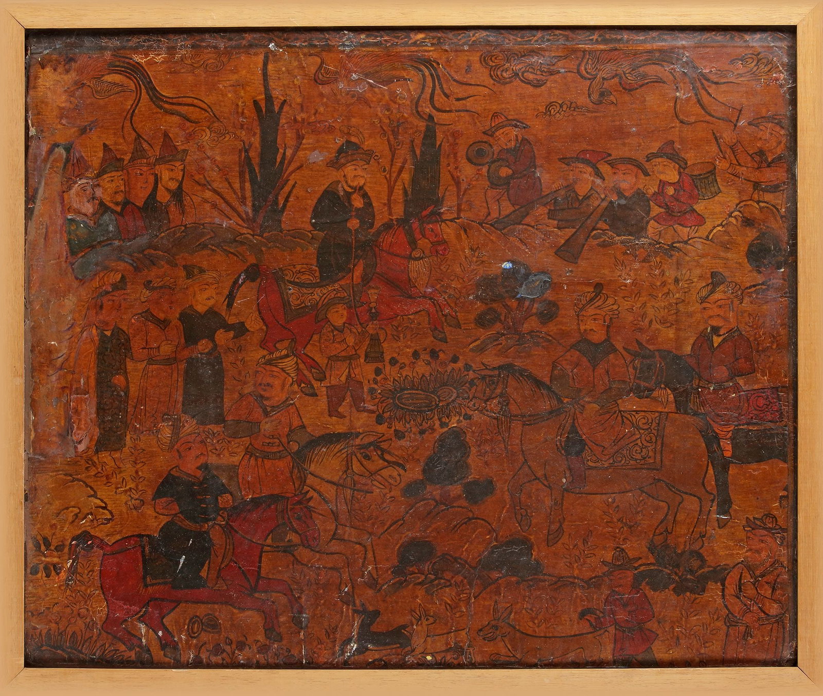 A QAJAR LACQUER PAPIER MACHE PANEL, PERSIA 19TH CENTURY: Of rectangular form, finely painted in polychrome and heightened with black and gold against a warm amber lacquer ground, depicting an animated courtly hunting procession set within a stylised rocky l