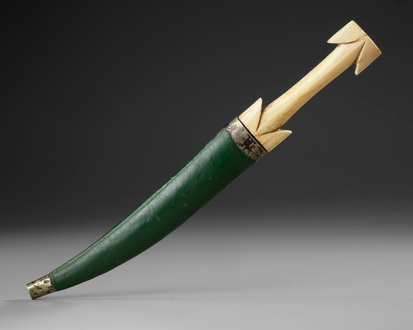 AN OTTOMAN BONE-HILTED DAGGER WITH SCABBARD, 18TH CENTURY: A finely crafted OttomaN dagger featuring a polished, double-edged curved steel blade with a pronounced central ridge. The carved bone hilt is distinguished by its elegant arrowhead pommel and stylize