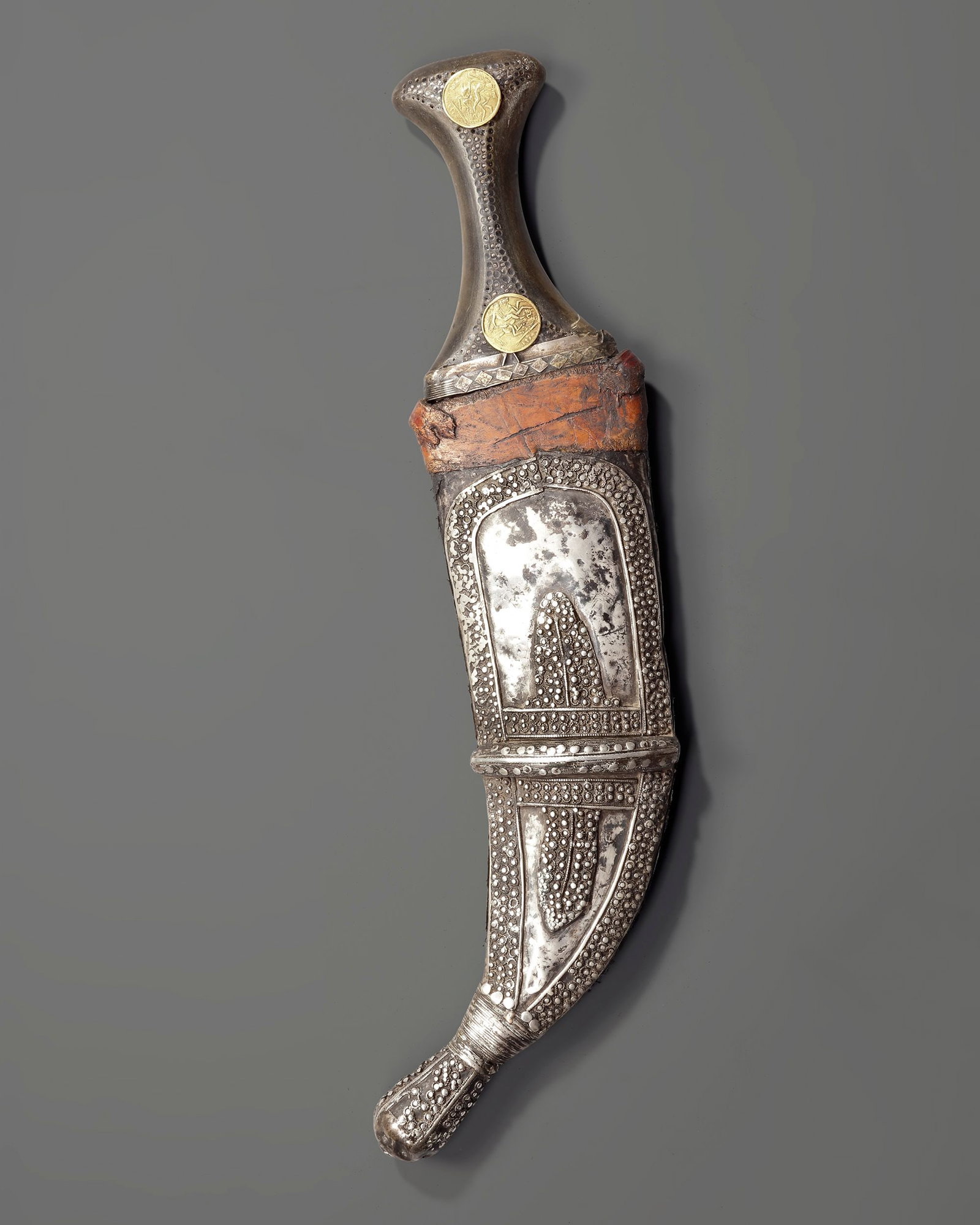 A SILVER YEMENI DAGGER, EARLY 20TH CENTURY: A finely crafted Yemeni dagger (jambiya) from the early 20th century, featuring a steel blade and a richly decorated silver hilt adorned with traditional granulation and rosette motifs. Length 36,5 cm