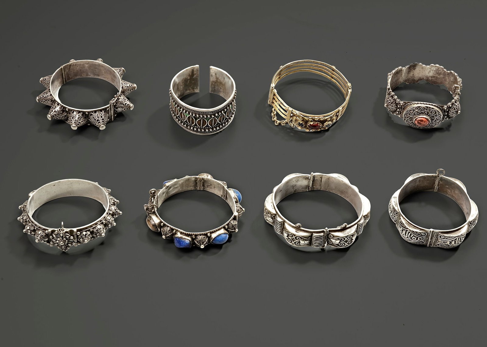 A GROUP OF EIGHT BRACELETS, 19TH-20TH CENTURY: A collection of eight ornate silver bracelets from Morocco, Yemen, Saudi Arabia, and Oman, dating back to the 19th century. Each piece showcases intricate craftsmanship, traditional motifs, and region