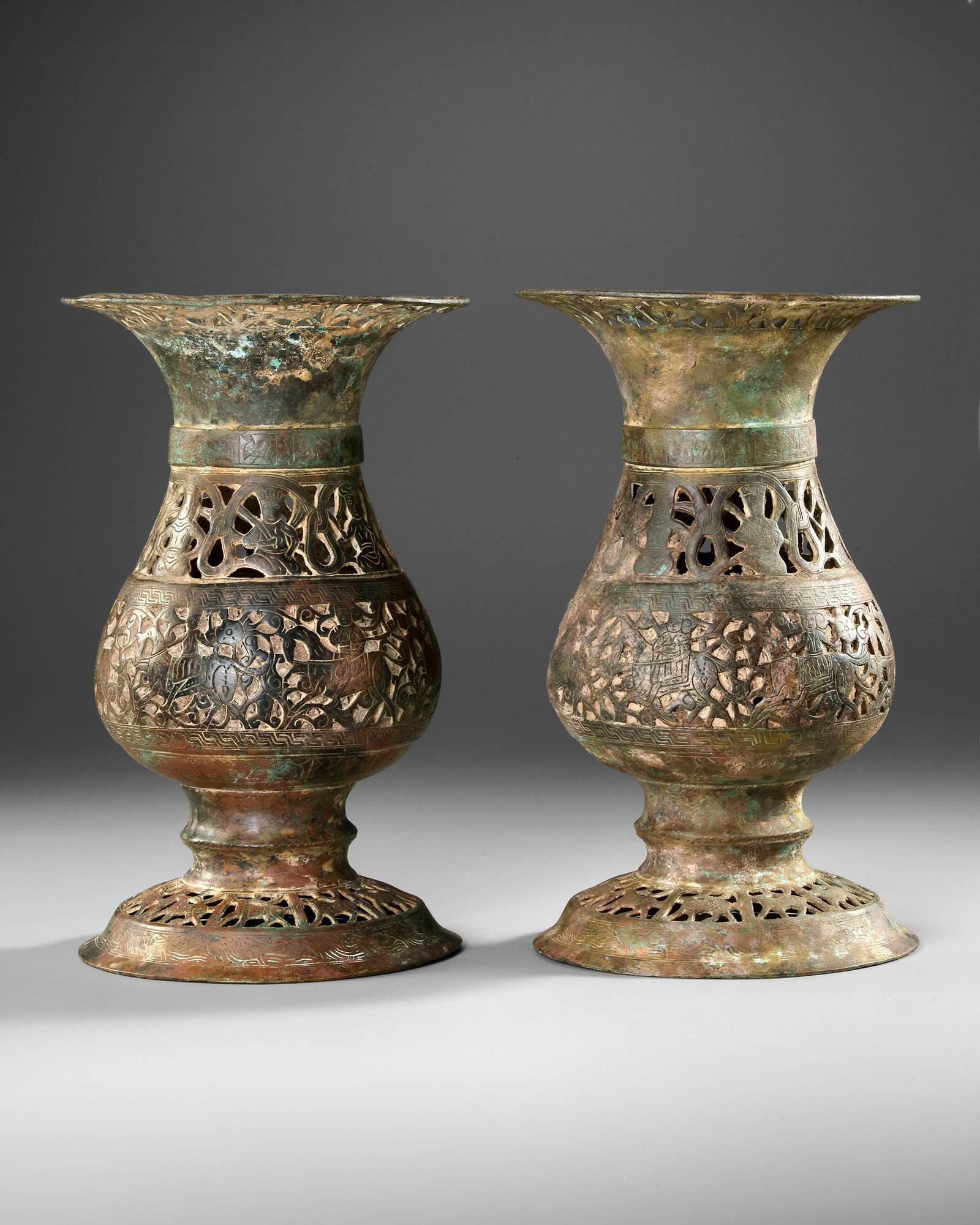A PAIR OF LARGE KHORASAN BRONZE VASES, PERSIA, 12TH CENTURY: A rare pair of Khorasan bronze vases from 12th-century Persia, characterized by their elegant pear-shaped bodies, flaring necks and high splayed bases. The surfaces are richly decorated with intricate