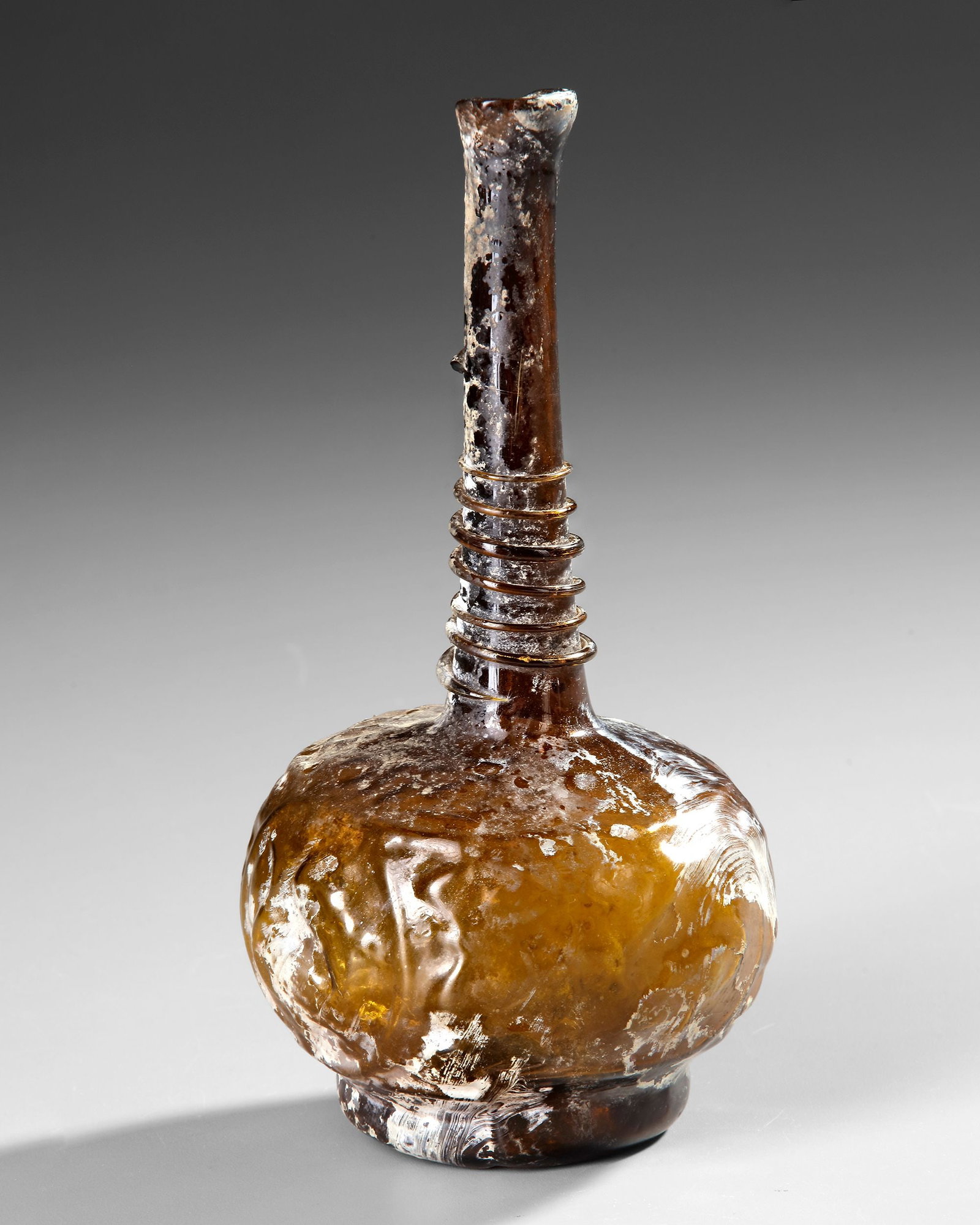 AN AMBER GLASS LOBED BOTTLE, PERSIA 9TH-11TH CENTURY (1 of 4)