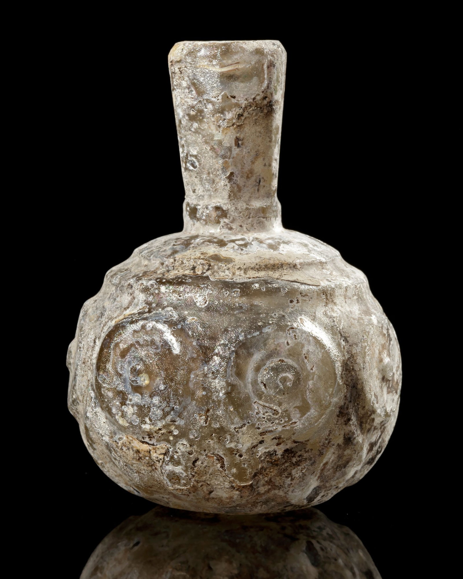 A WHEEL-WHEEL-CUT CLEAR GLASS BOTTLE NORTH EAST PERSIA, 9TH-10TH CENTURY: A wheel-cut clear glass bottle from northeastern Persia, dating to the 9thâ€“10th century. It features a globular body and a short cylindrical neck, formed by free-blowing and decorated with f