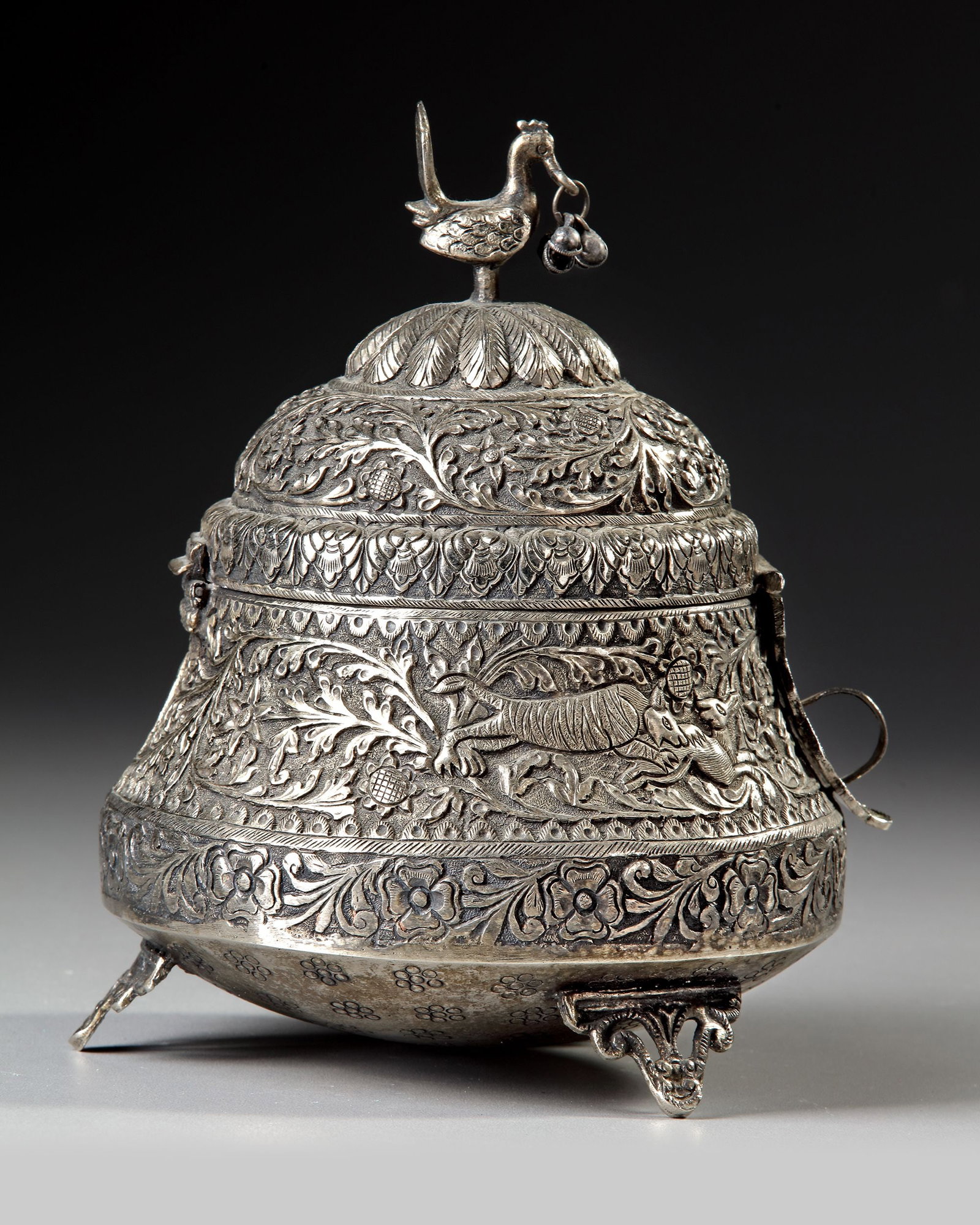 A SILVER INCENSE BURNER, INDIA, 19TH CENTURY: A silver incense burner with waisted body and hinged domed lid on three feet, decorated in repouss?© with animals amongst foliage. Height 21.5 cm. 720 gr.