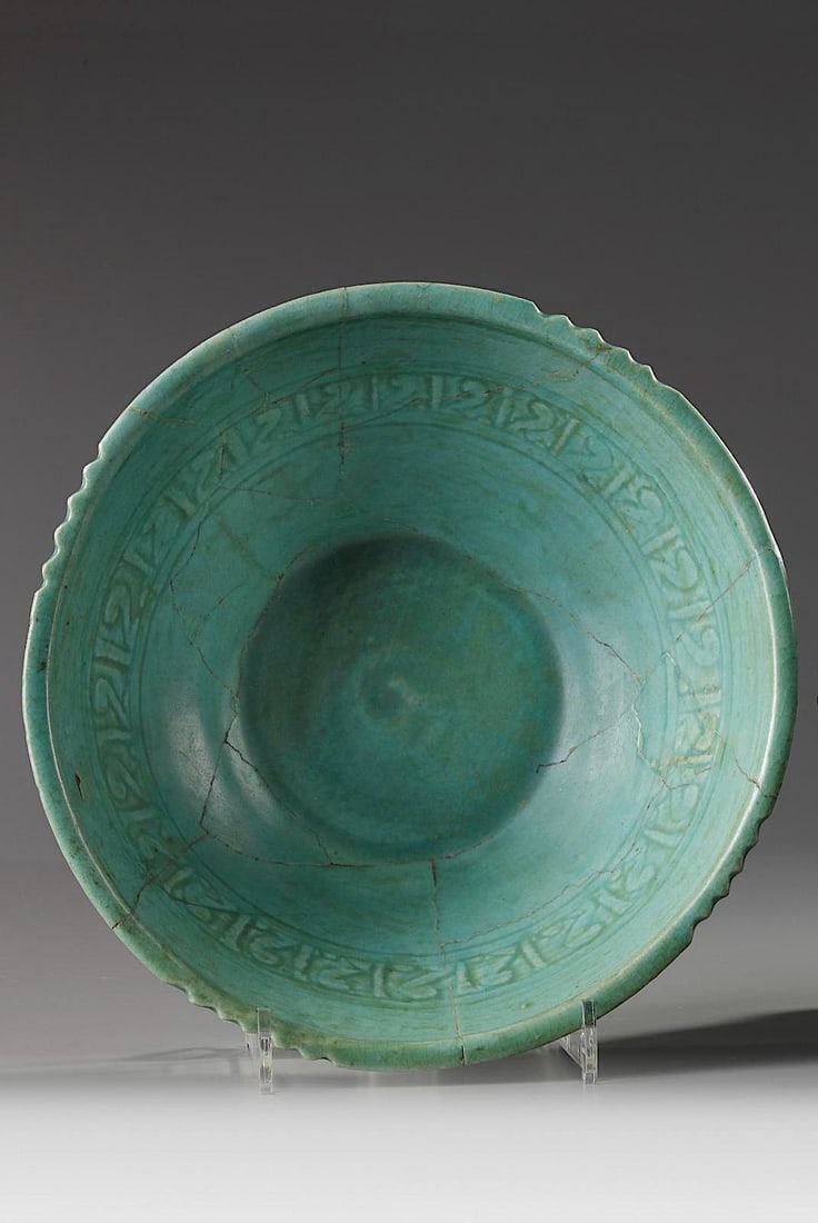 A PERSIAN KASHAN BOWL, 12TH-13TH CENTURY: The bowl is with a partially toothed rim and decorated to the interior with a band of a geometric designs and further covered with a turquoise glaze. Height 8.5 cm. Diameter 23 cm.