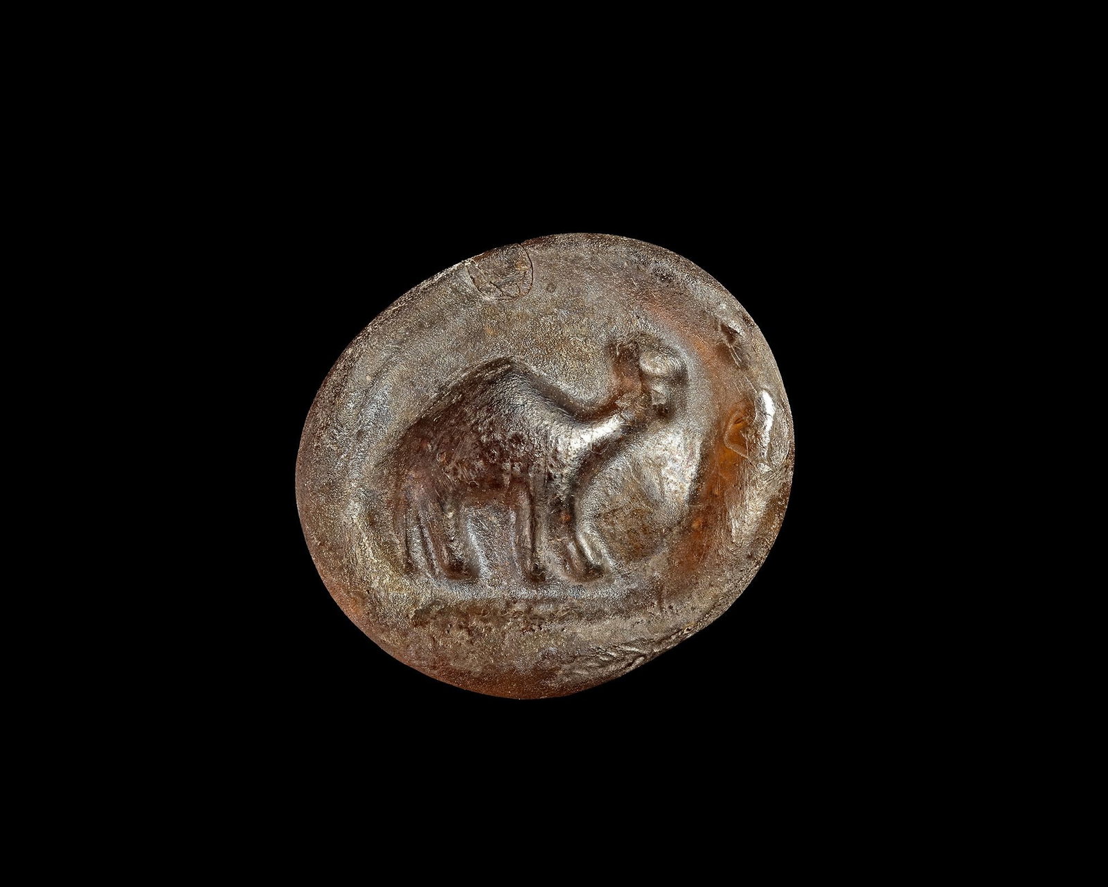AN EARLY ISLAMIC GLASS WEIGHT, 10THâ€“11TH CENTURY: An early Islamic circular glass weight of amber-brown colour, moulded in relief with the figure of an animal, possibly a camel. The reverse is plain and displays natural surface weathering, deposits a