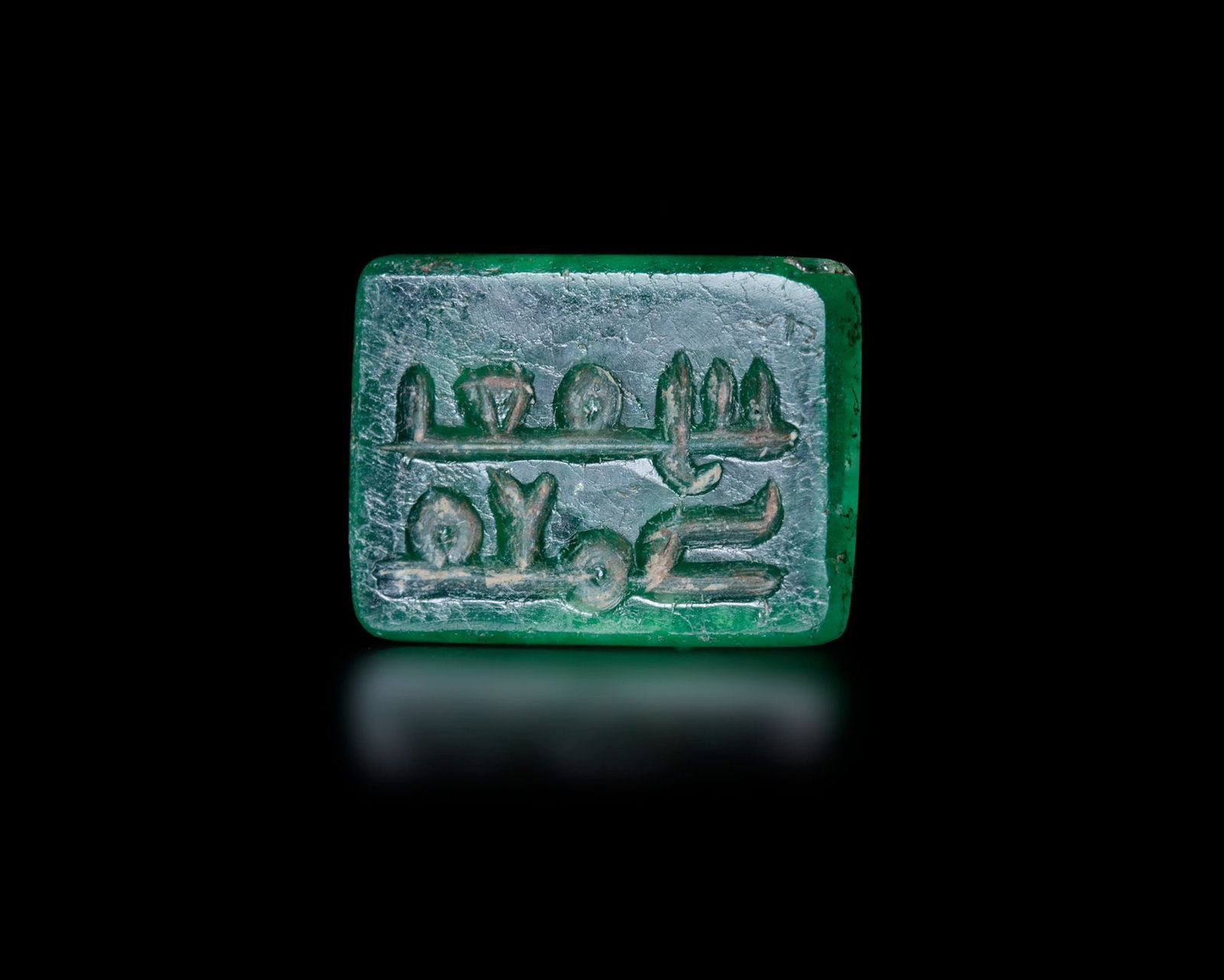 A KUFIC-INSCRIBED GREEN HARDSTONE SEAL, 4THâ€“5TH CENTURY AH/10THâ€“11TH CENTURY AD: A finely carved rectangular green hardstone seal engraved in elegant early Kufic script arranged in two registers separated by a horizontal rule. The inscription is read as ?¨???‡???? ?…?­?…??