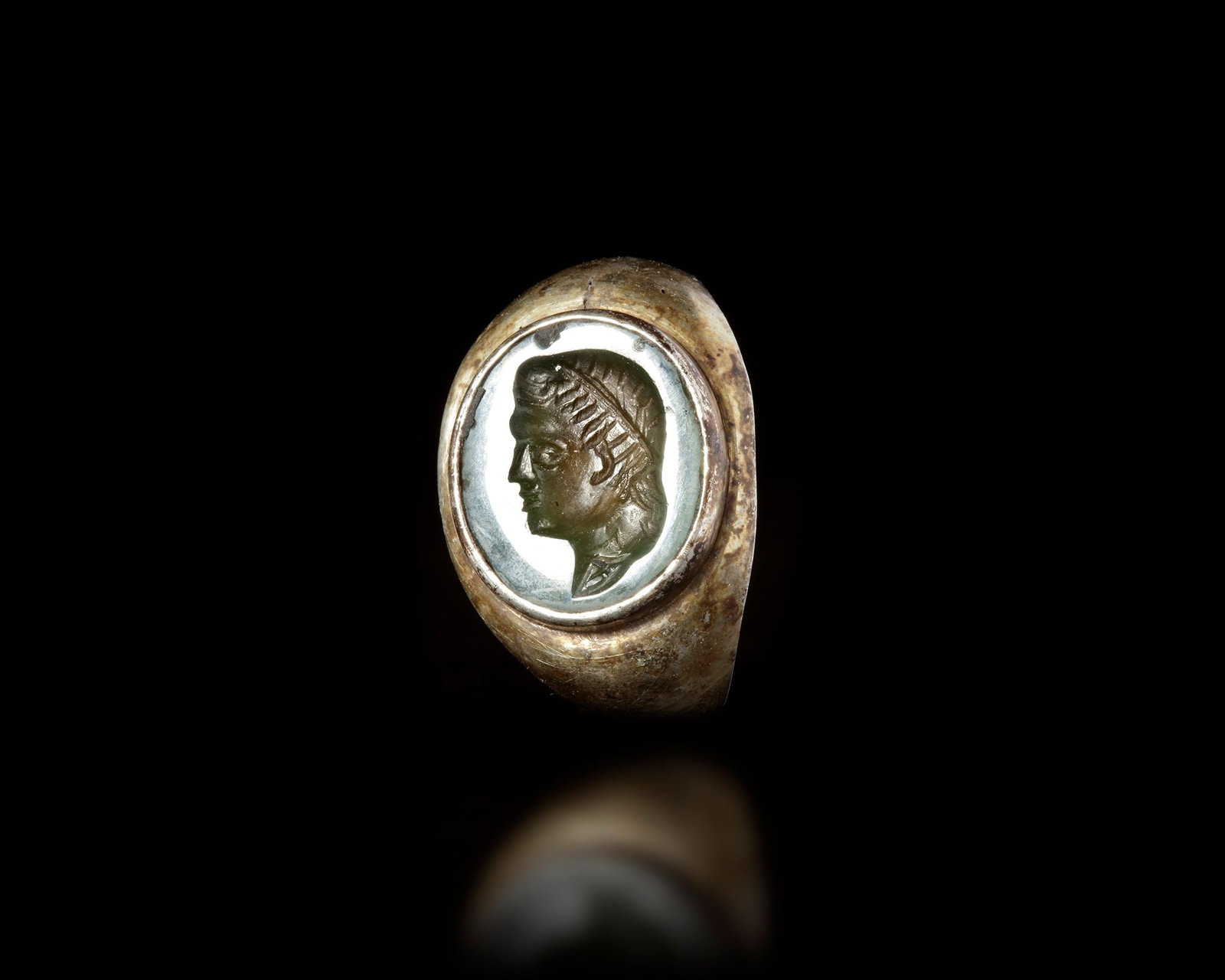 A SILVER INTAGLIO RING, 19TH CENTURY: A vintage silver ring featuring a finely carved intaglio portrait in profile. The bezel holds an oval inset showing a classical-style male figure, rendered with detailed hair and strong facial feature