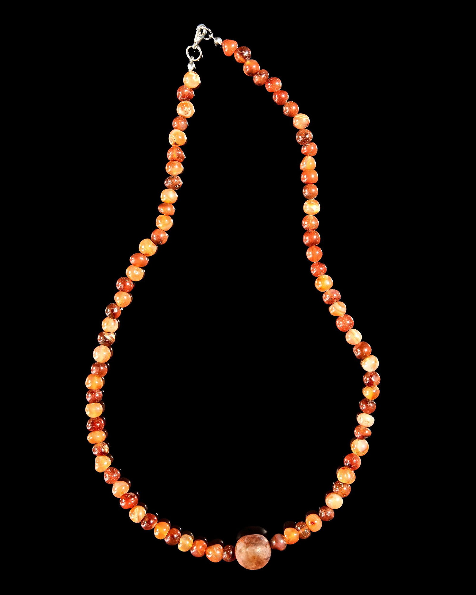 A BANDED AGATE & CARNELIAN BEAD NECKLACE: Beautiful necklace featuring 81 polished carnelian stone beads in rich shades of orange, red, and amber with natural color variation and translucency. A larger round focal bead at the center adds bala