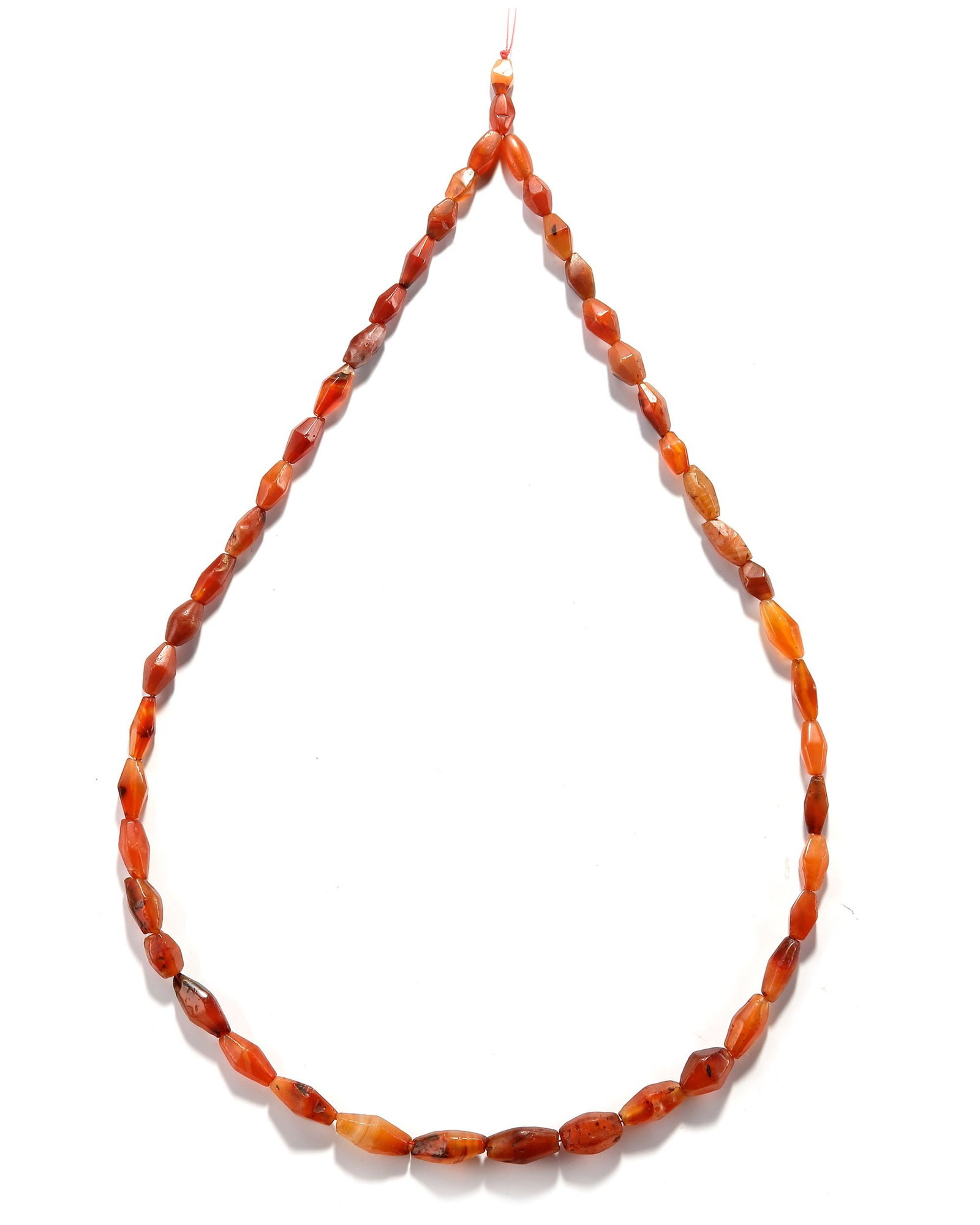 A CARNELIAN NECKLACE, NEAR EASTERN, 3RD MILLENNIUM BC: Elegant strand of faceted natural carnelian beads in elongated barrel and oval forms, displaying rich shades of orange, amber, and reddish-brown. The beads exhibit attractive translucency, subtle agat