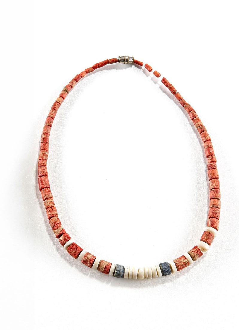 A NATURAL CORAL BEAD NECKLACE: Elegant graduated necklace composed of cylindrical red coral beads displaying natural color variation and organic surface texture, accented with white and blue spacer beads. Restrung with a magnetic c